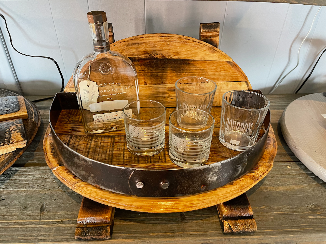 A wooden tray with a bottle and three glasses on it.