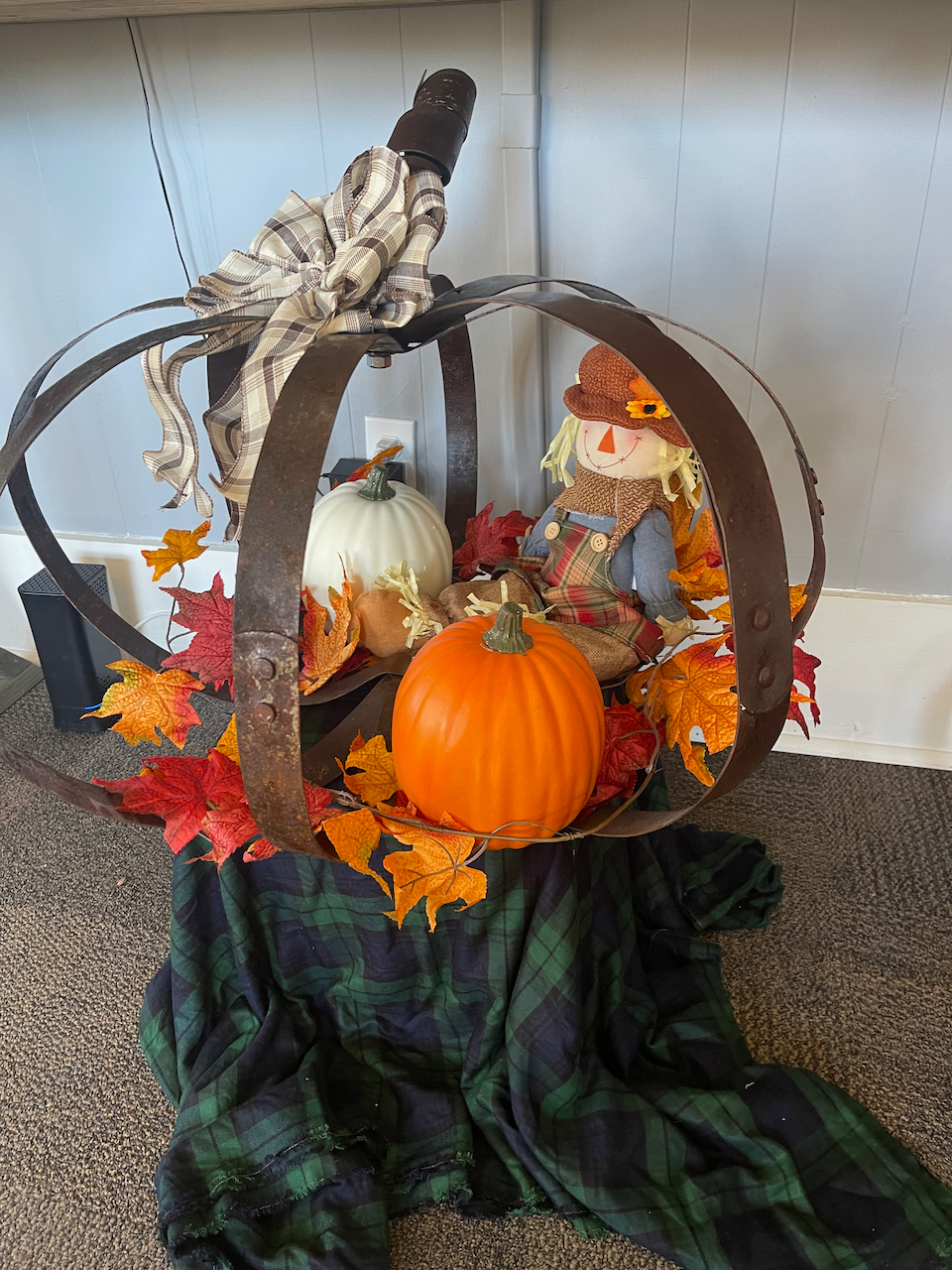 A scarecrow is sitting in a pumpkin surrounded by pumpkins and leaves.