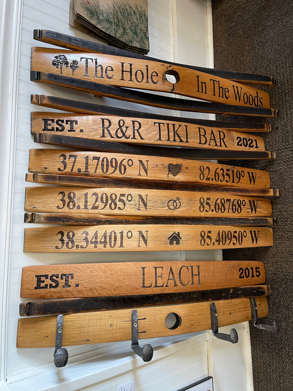 A row of wooden hooks with the names kamer and pat berger written on them