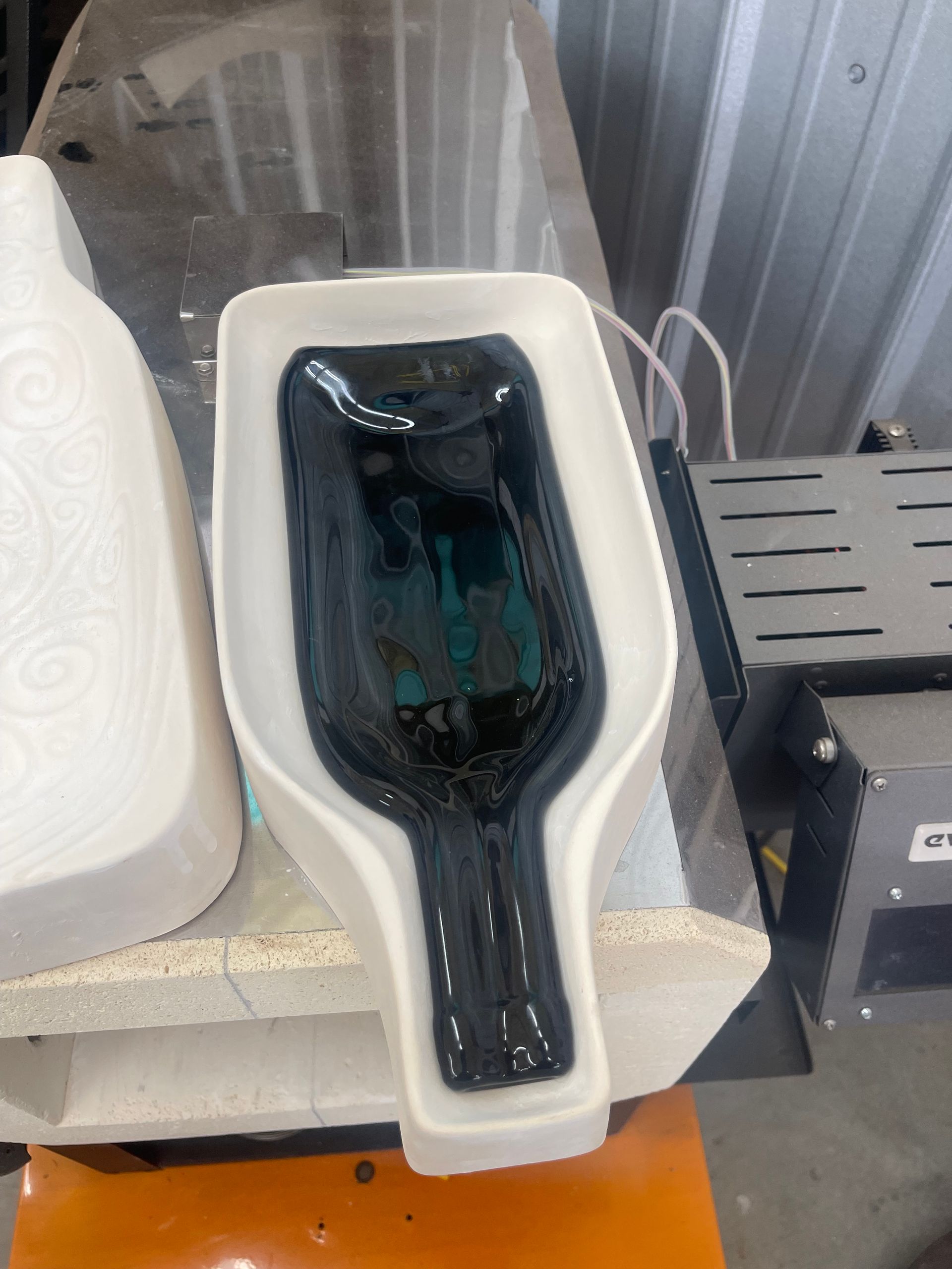 A bottle is sitting in a mould on a table.