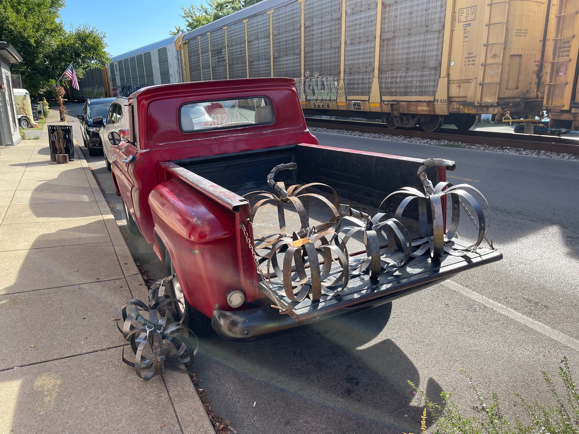 A red truck with bicycles in the back is parked on the side of the road.