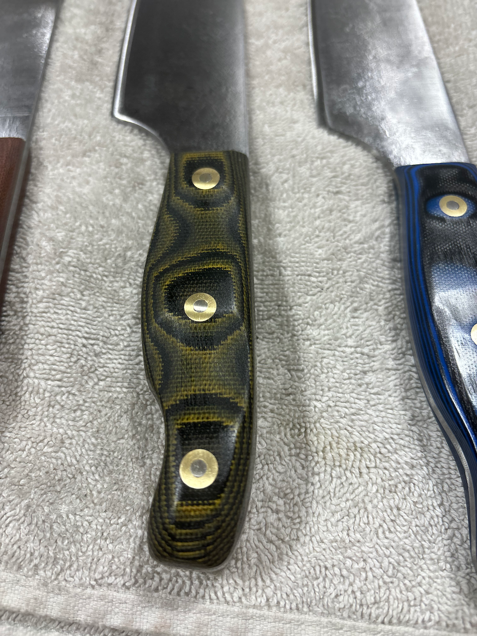 A group of knives are sitting on top of a towel on a table.