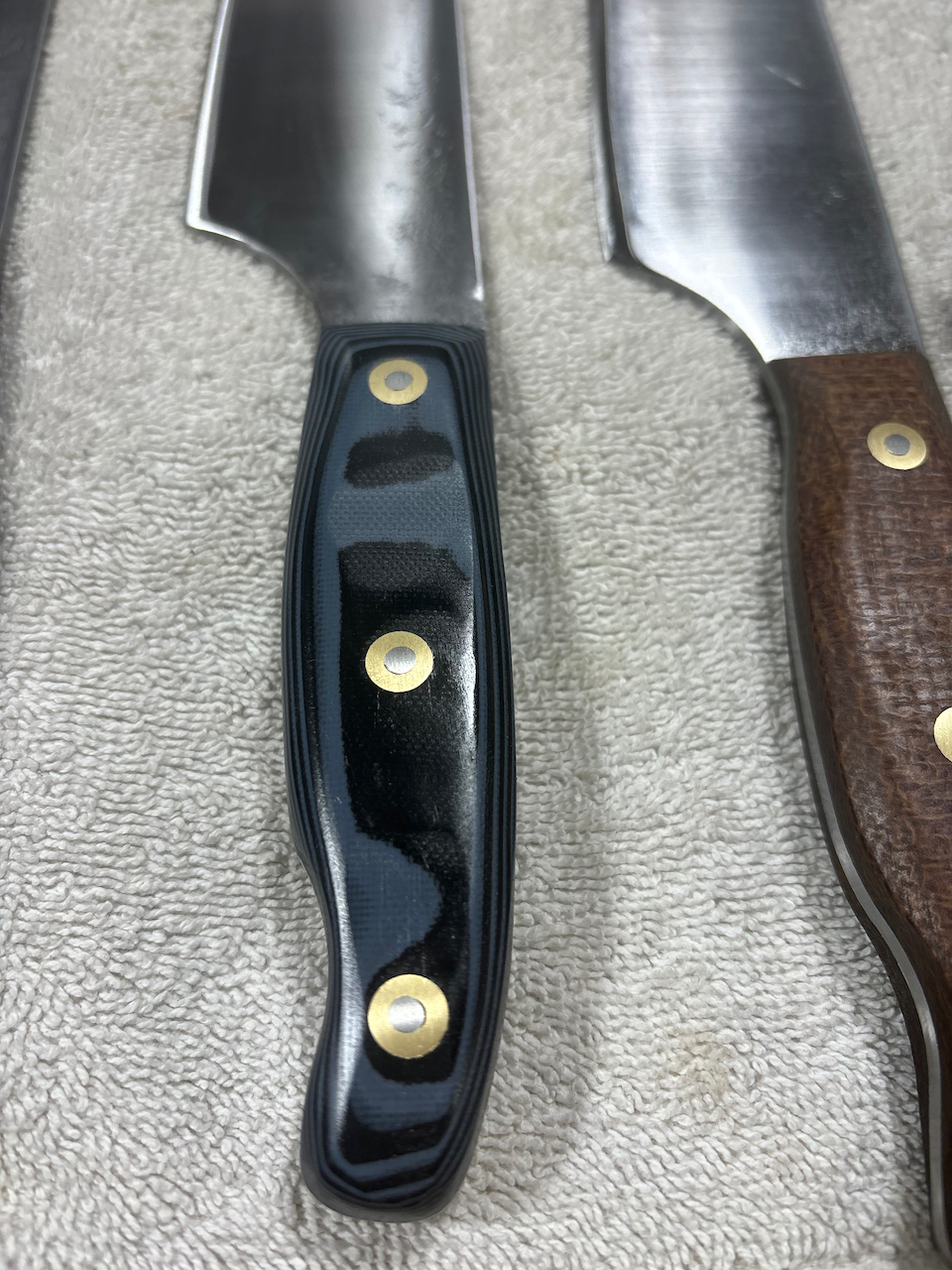 A close up of three knives with wooden handles on a towel.