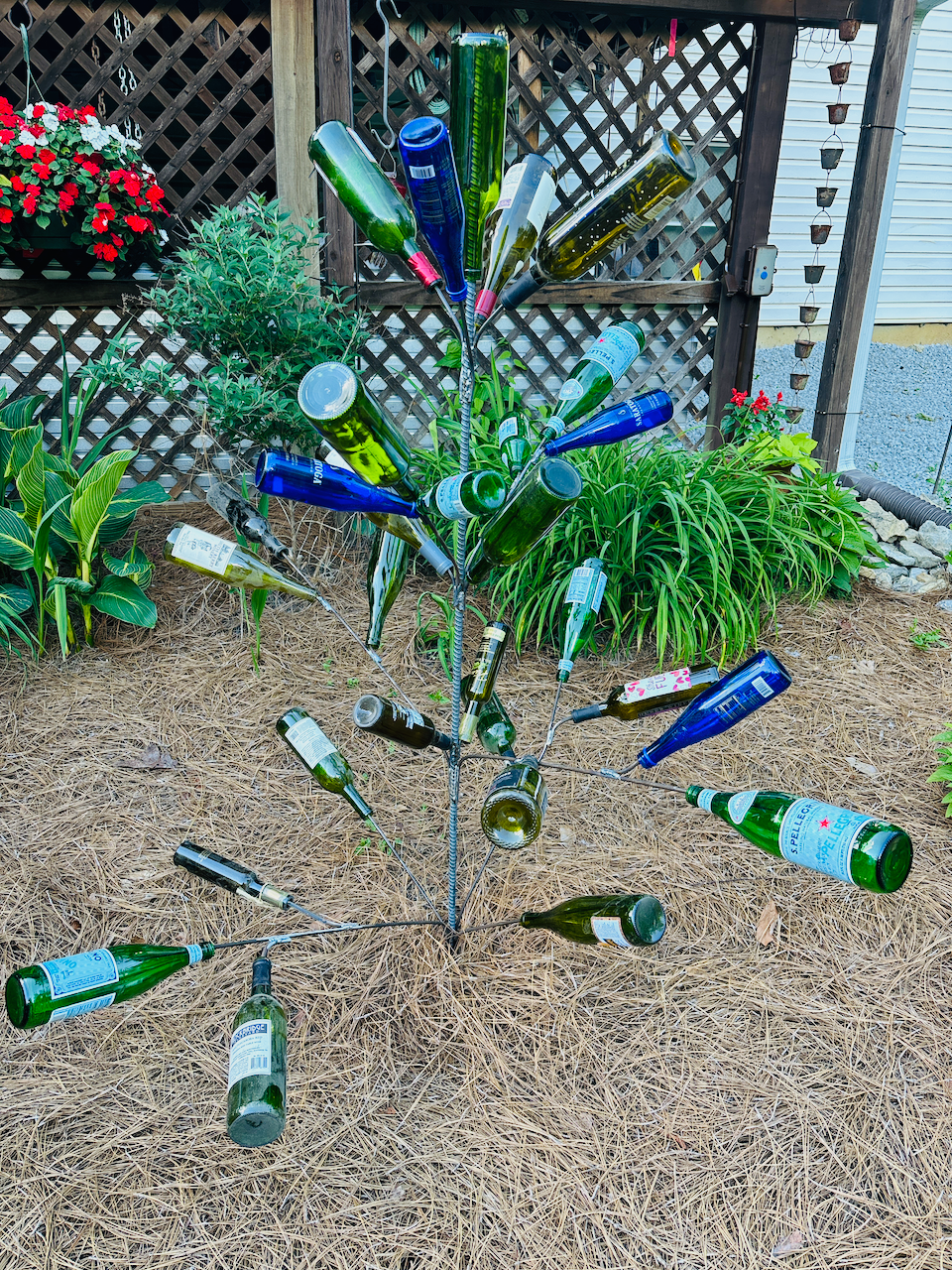A tree made out of empty wine bottles in a garden.