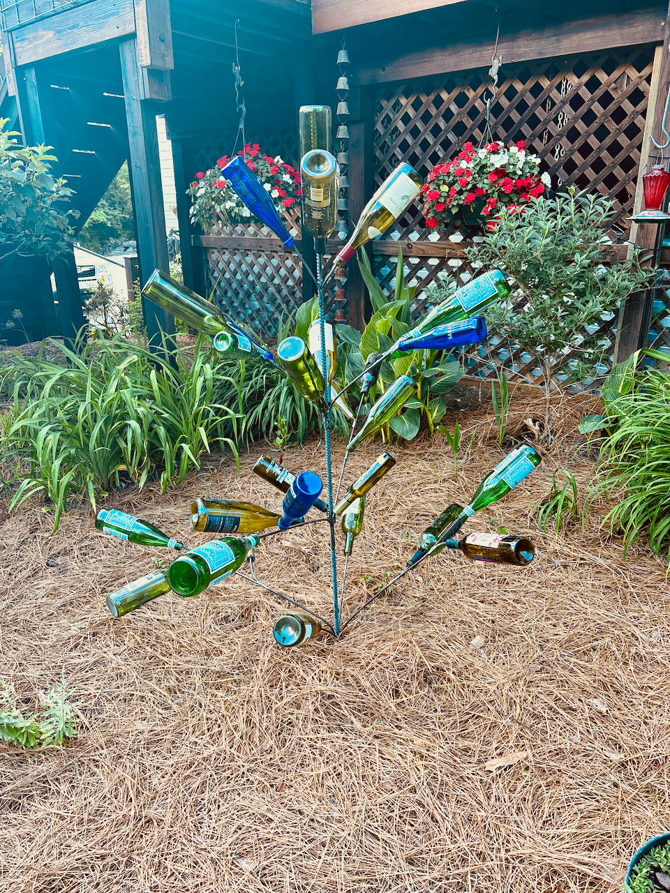 A tree made out of empty wine bottles in a garden.