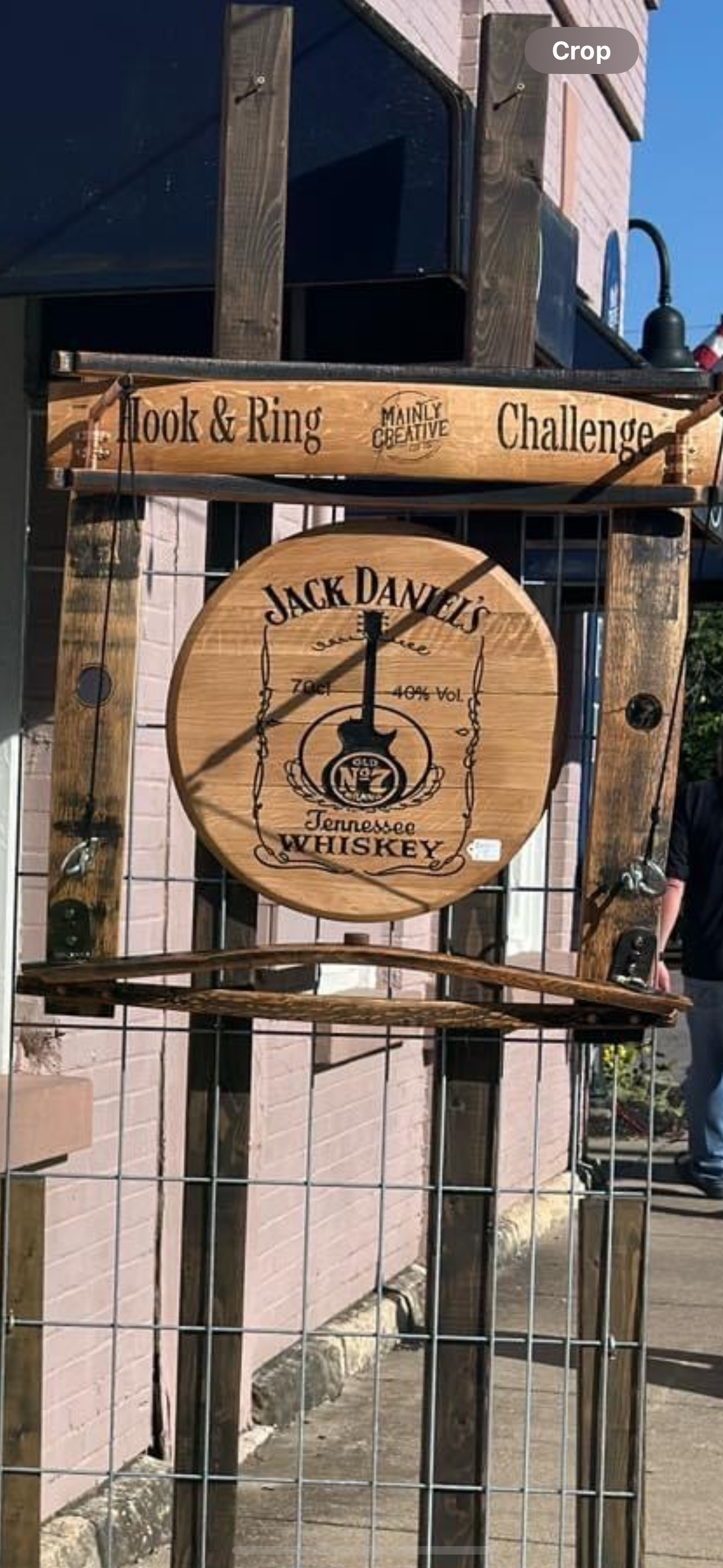 A wooden sign with a clock on it is hanging on a fence.