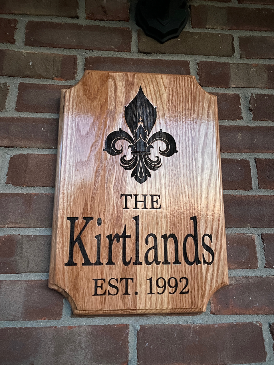 A wooden sign on a brick wall says the kirtlands est 1992