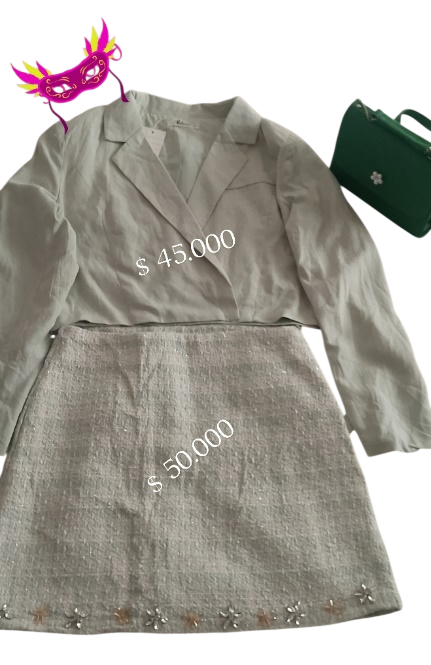 Blazer beige y traje de falda con precios de 45.000 y 30.000 dólares. Cerca hay un maletín verde y una mascarilla morada.