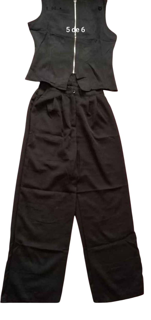 Top negro sin mangas con cremallera, combinado con pantalones negros de pierna ancha.