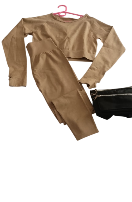 Conjunto deportivo color verde azulado (top y leggings) con bolso bandolera negro, colgado en una percha rosa.