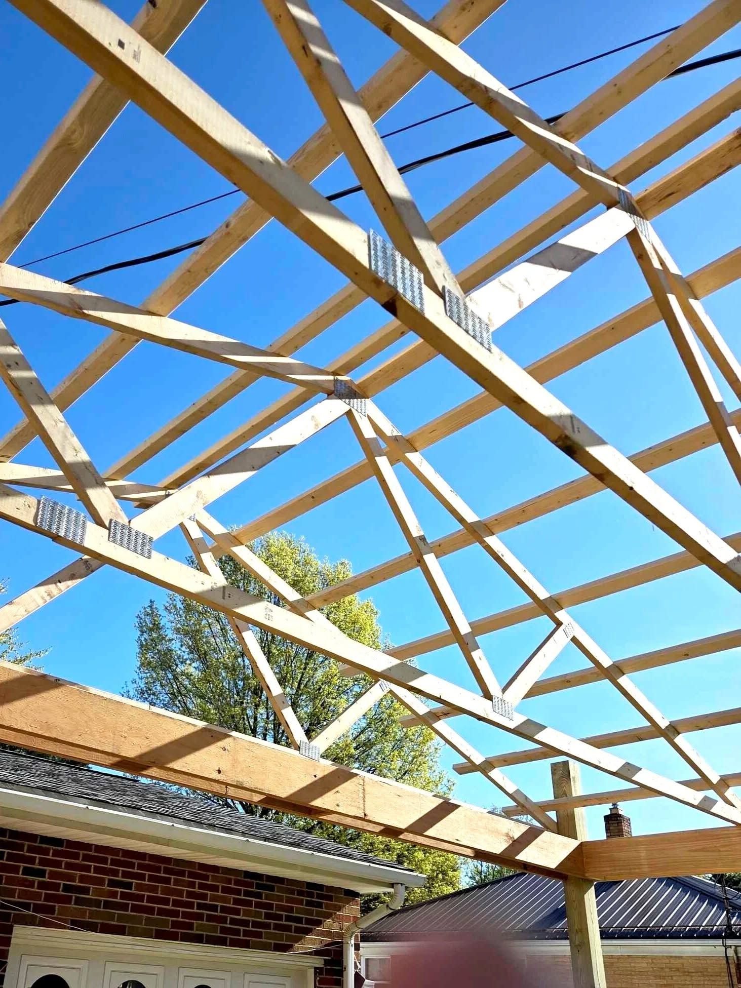 Wooden beams forming the framework of a roof against a blue sky.