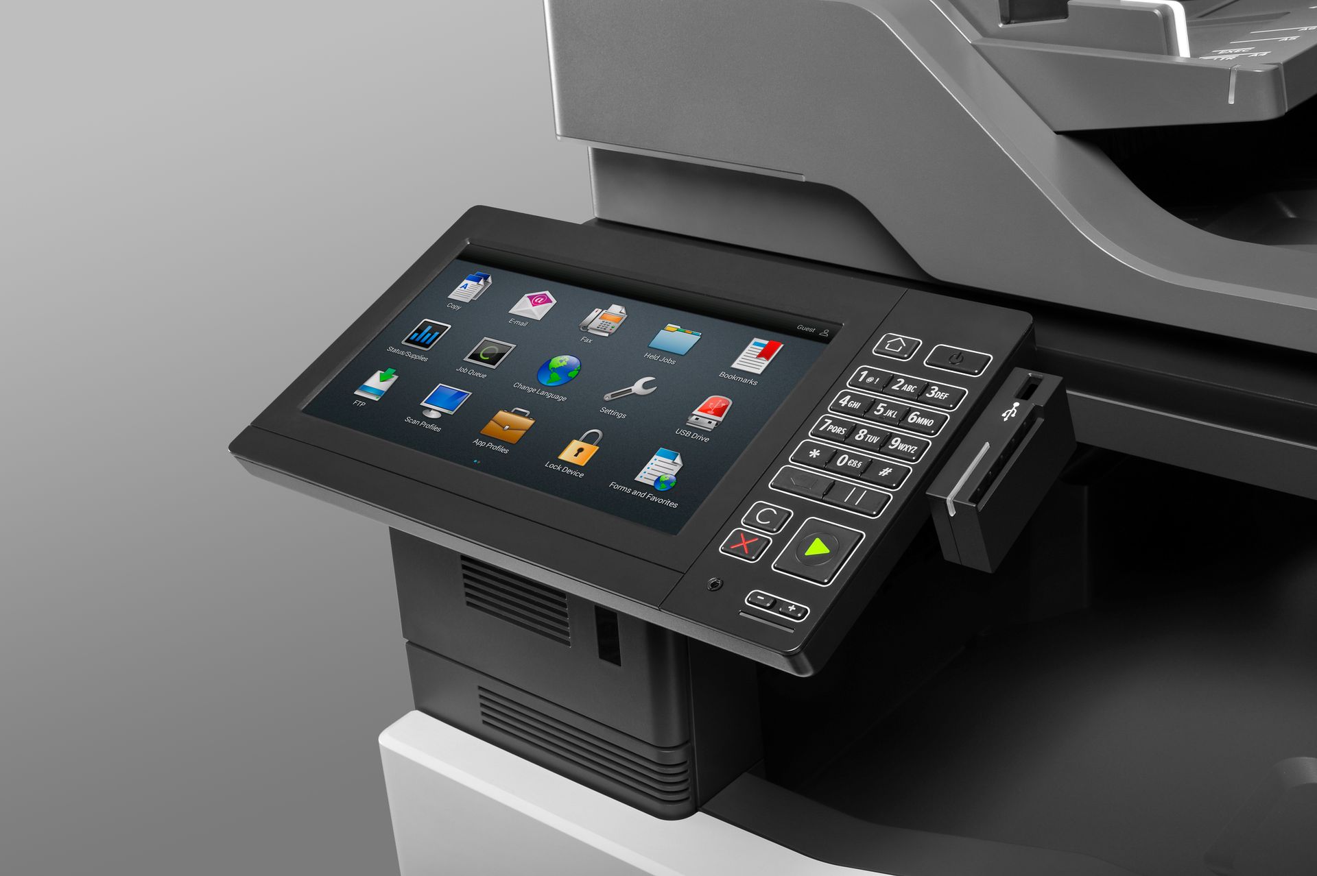 Zbliżenie panelu sterowania drukarki wielofunkcyjnej z ekranem dotykowym wyświetlającym różne ikony aplikacji i przyciski.