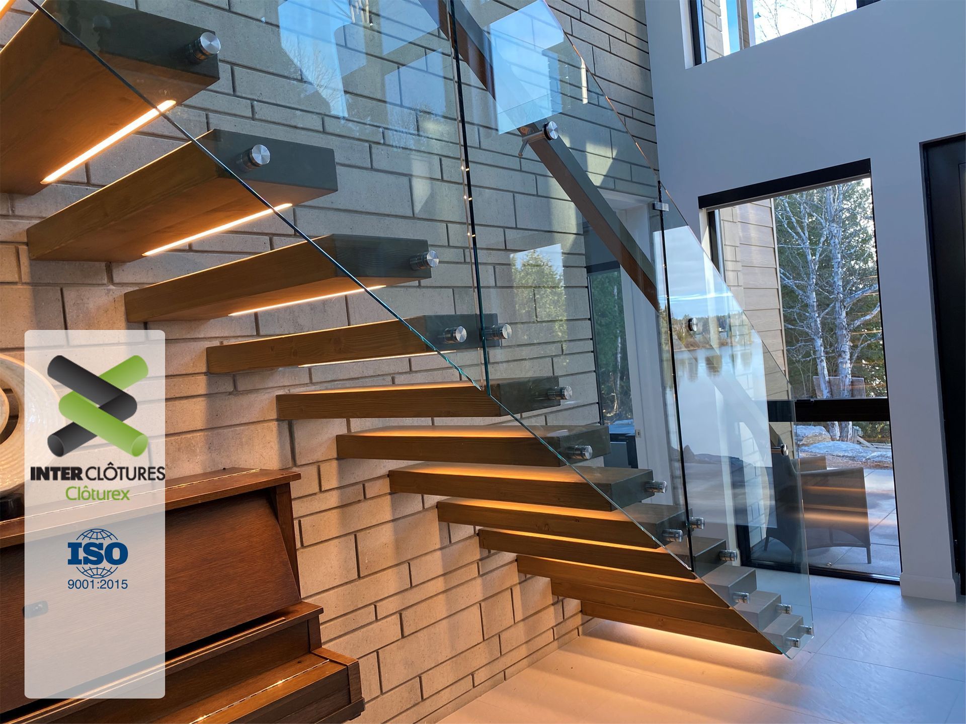 Un escalier en bois avec une rampe en verre dans une maison.