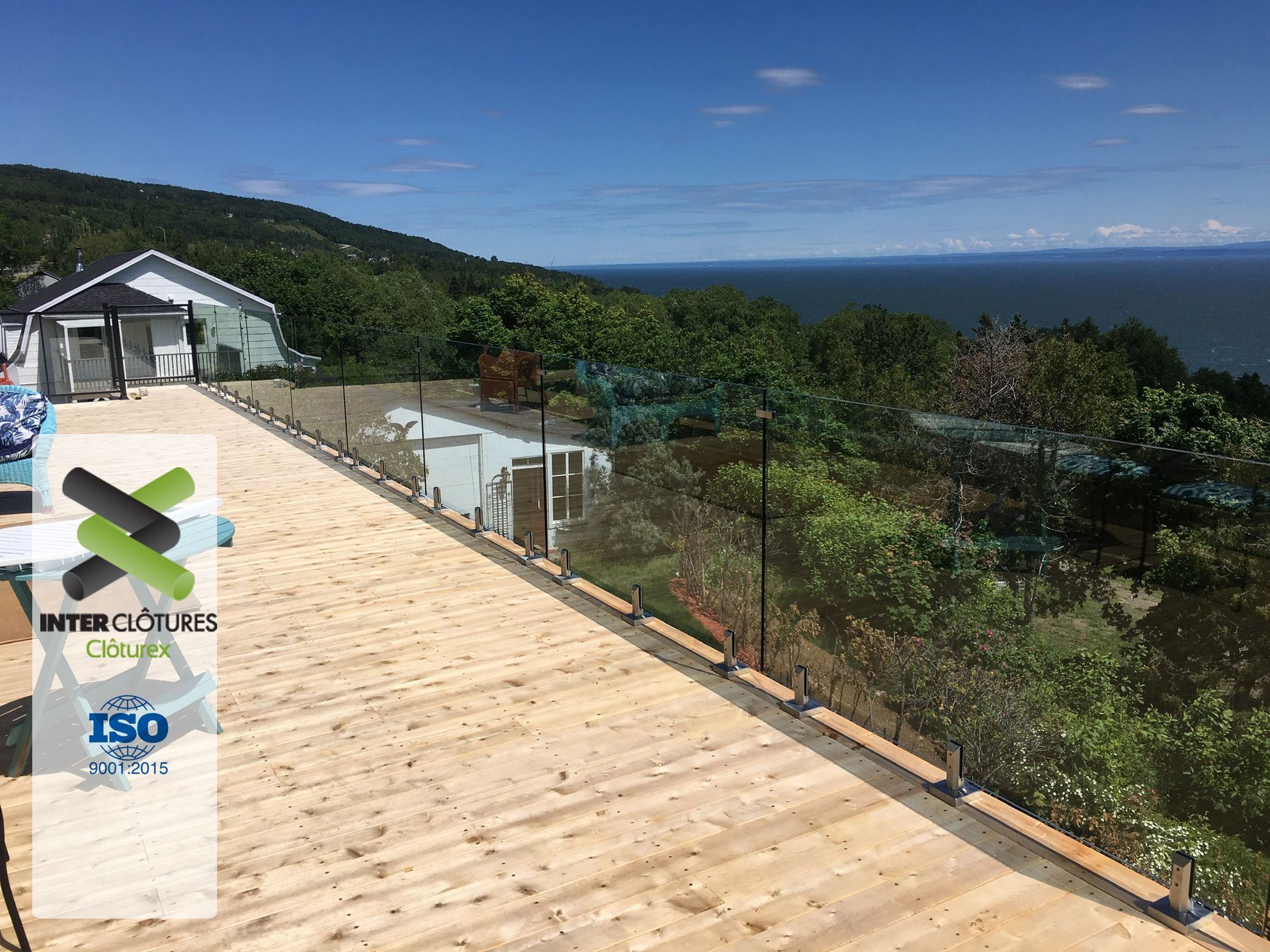 Une terrasse en bois avec une balustrade en verre donnant sur l'océan.
