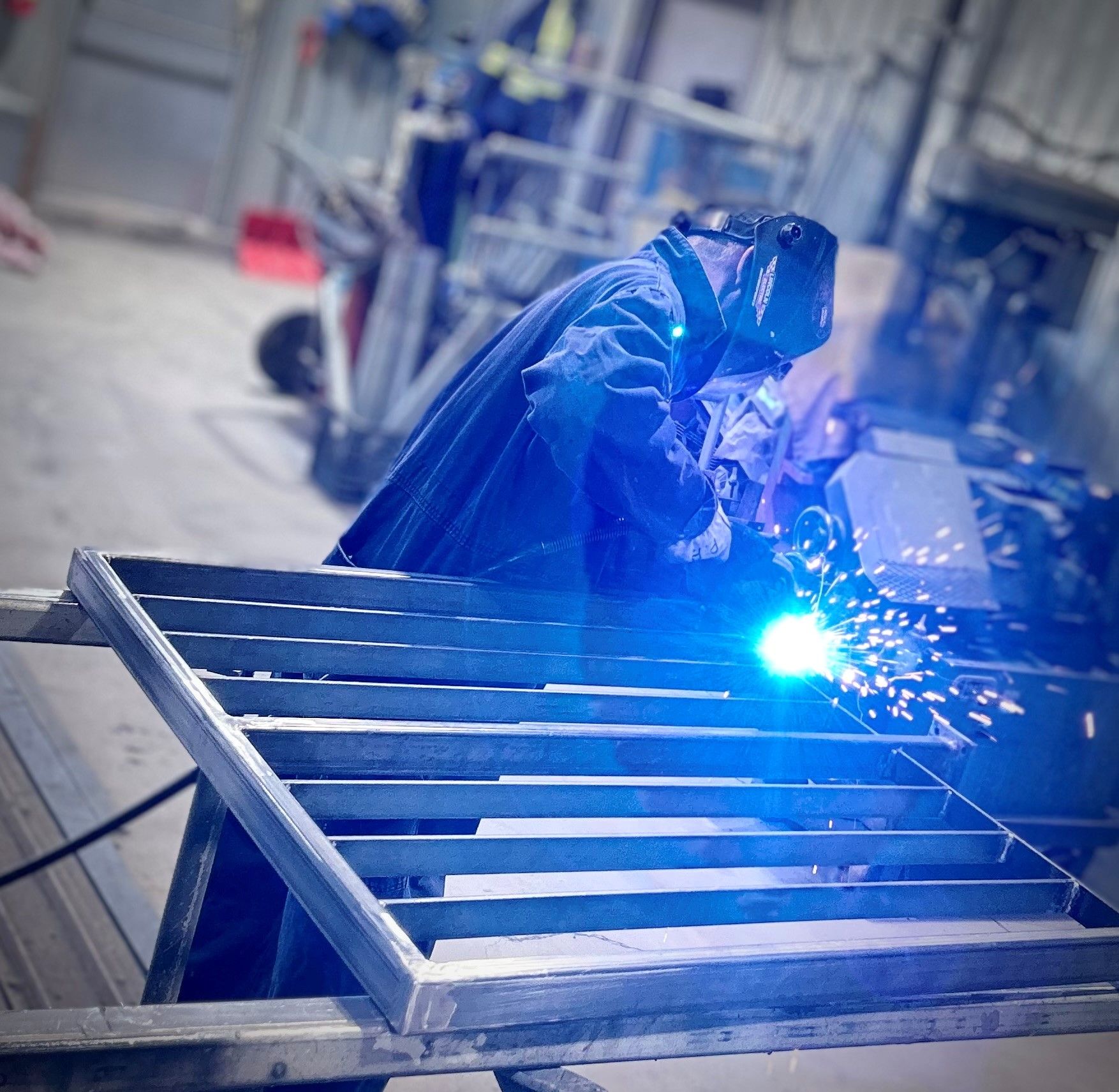 Un homme soude un morceau de métal dans une usine