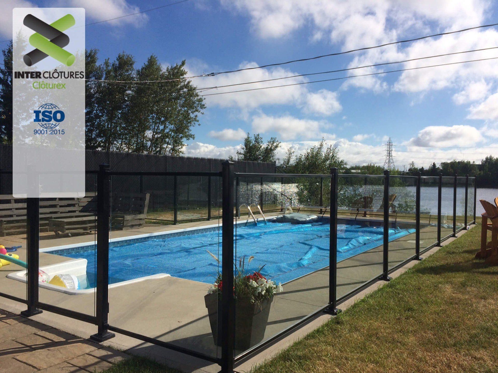 Une clôture en verre entoure une grande piscine