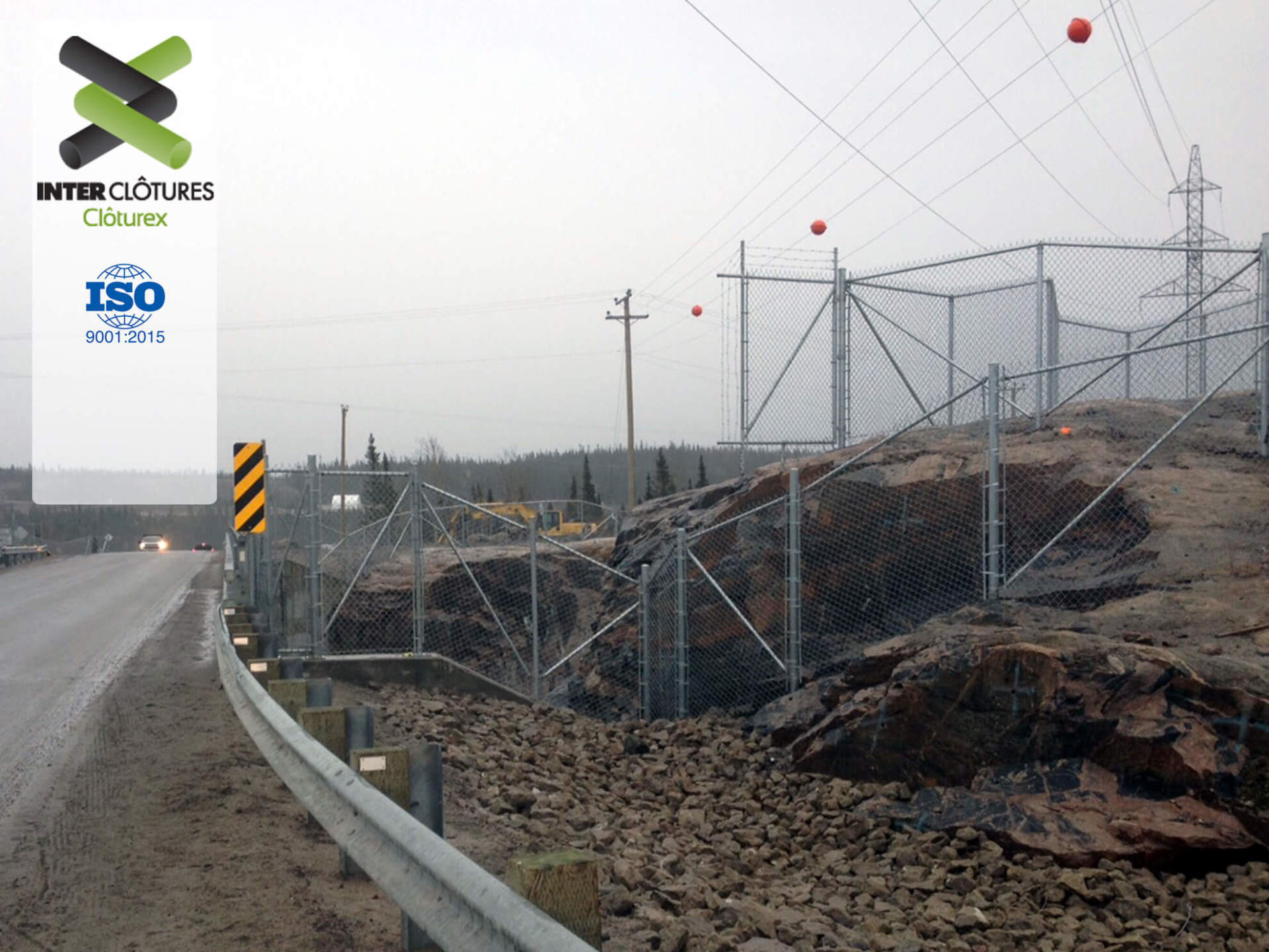 Une clôture entoure une colline rocheuse à côté d'une autoroute.