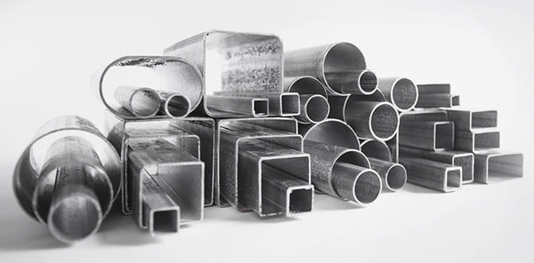 Un tas de différents types de tuyaux métalliques sont empilés les uns sur les autres.