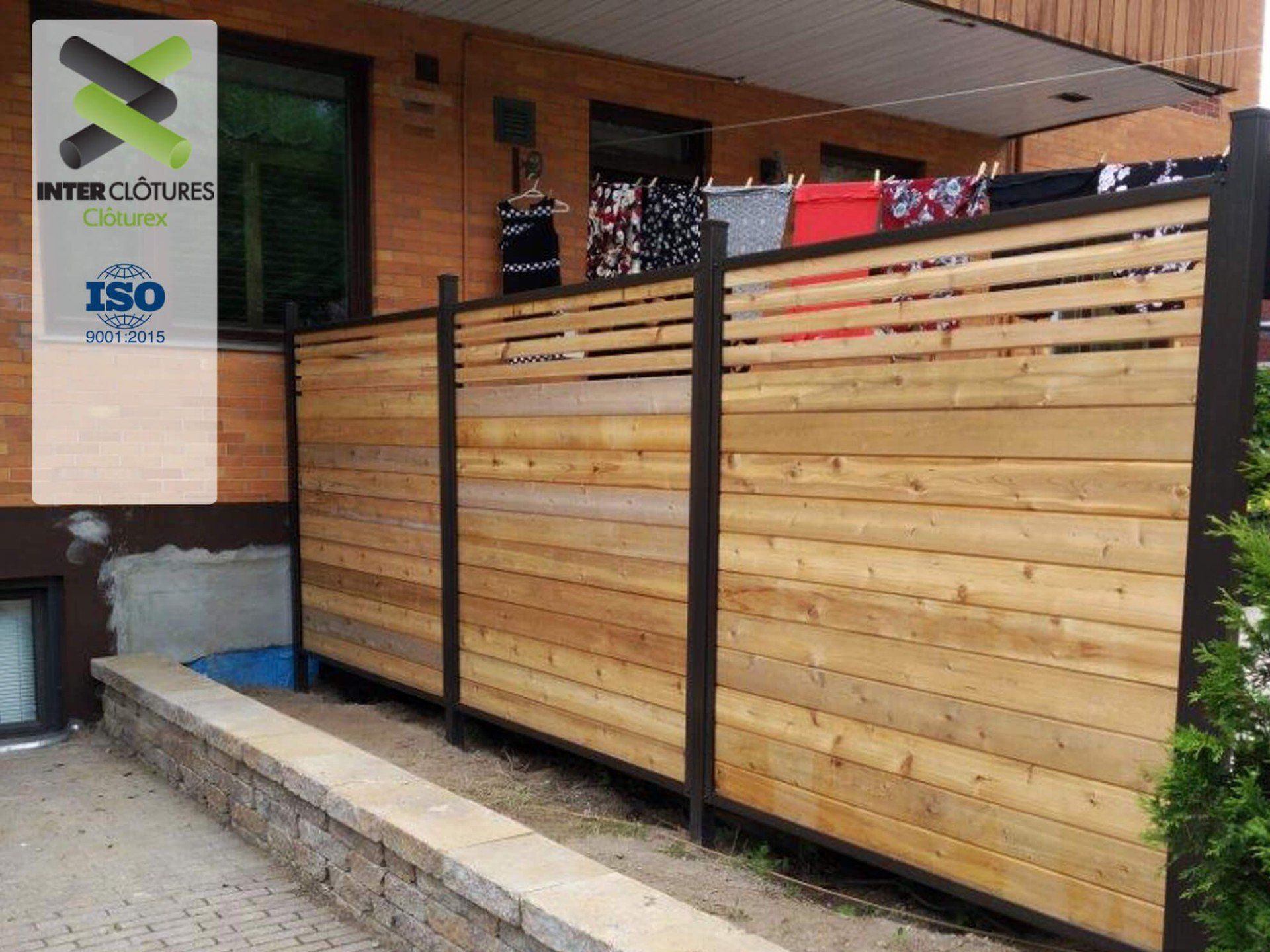 Une clôture en bois se trouve devant un bâtiment en briques