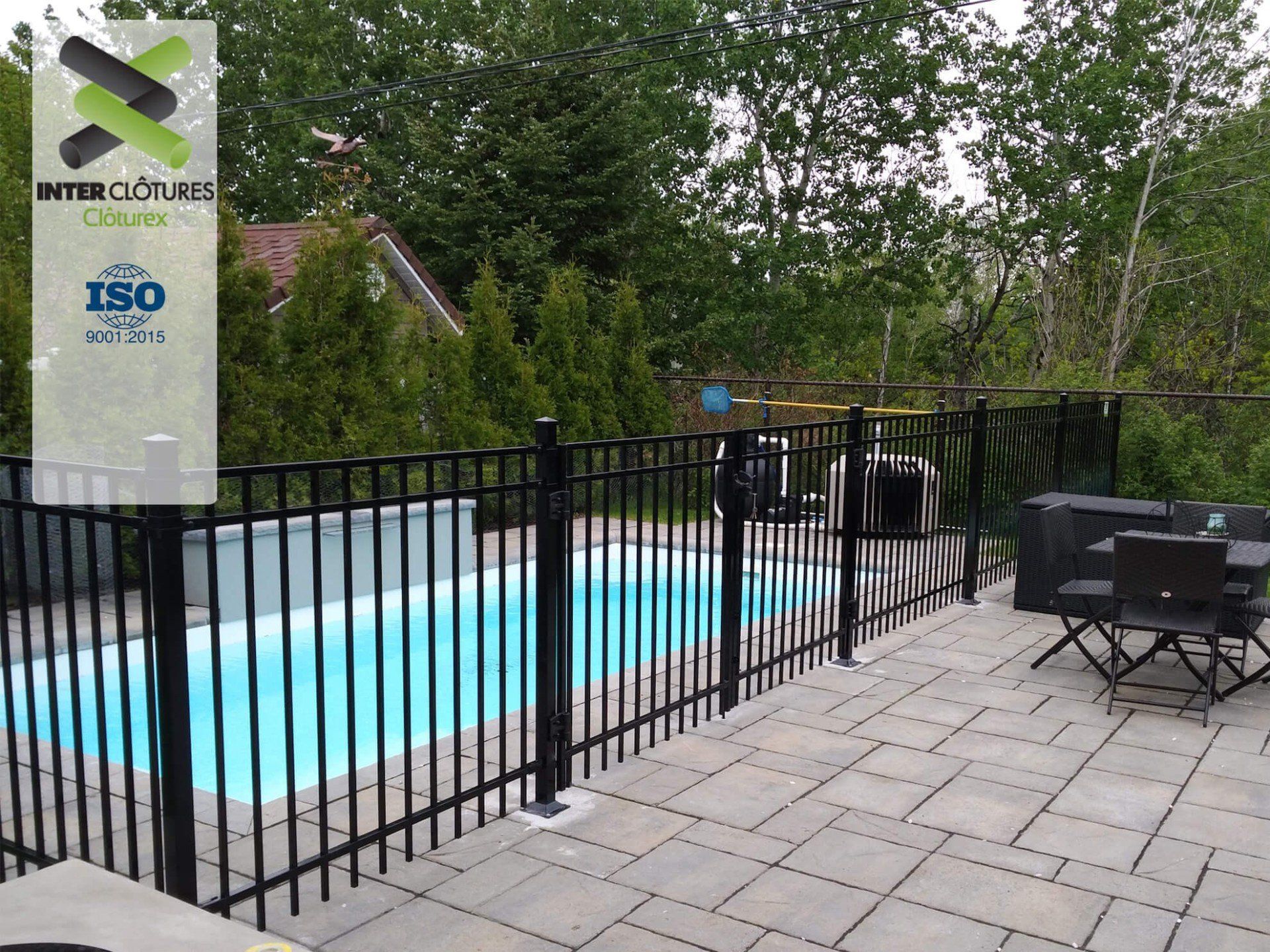 Une clôture en métal noir entoure une piscine