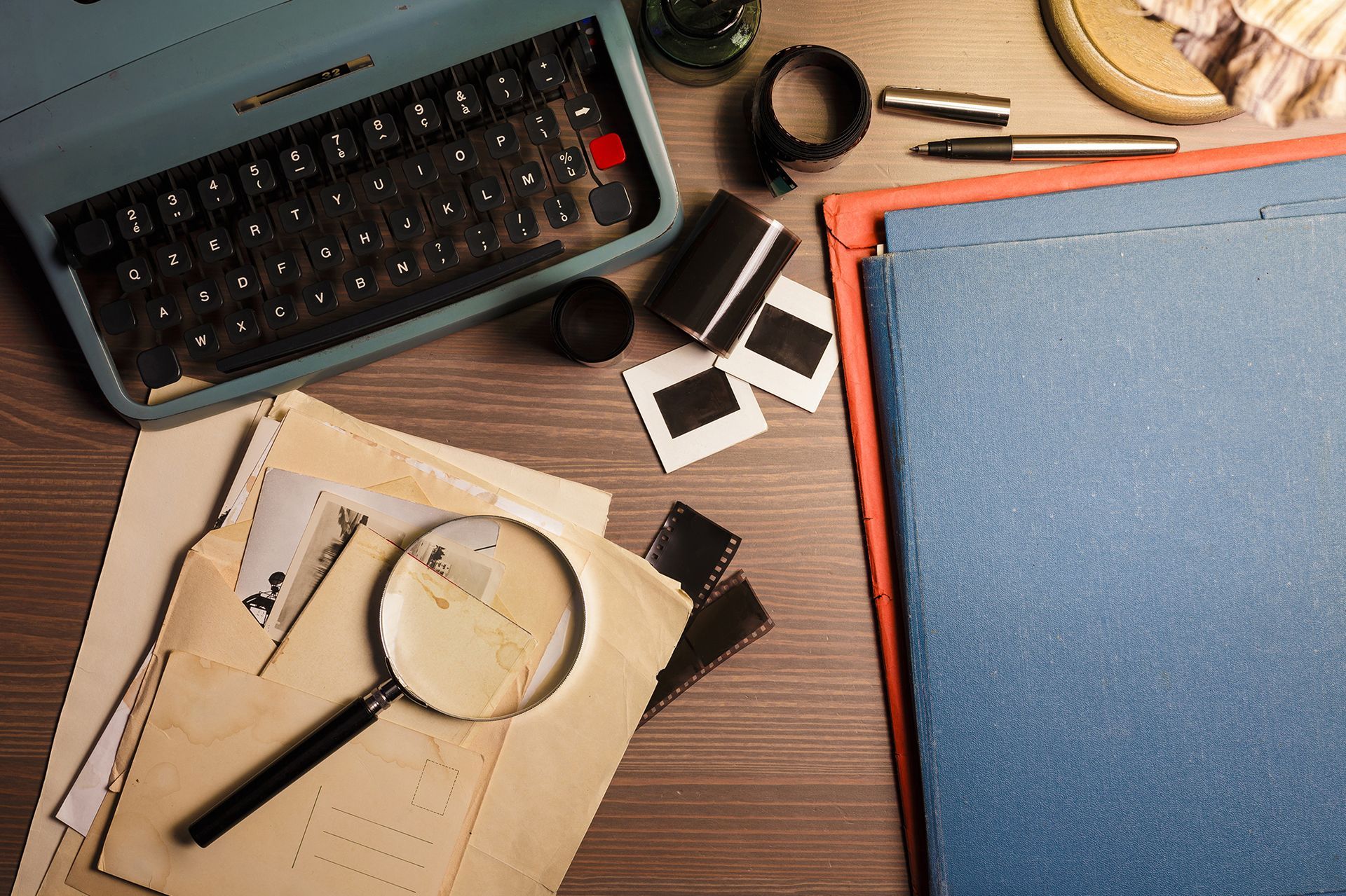A magnifying glass is on a table next to a typewriter.