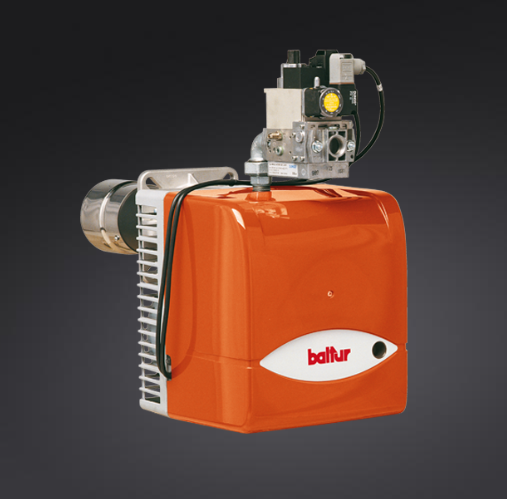 Bruciatore Baltur arancione con scarico argentato, cablaggio nero e scatola di controllo nera e gialla.