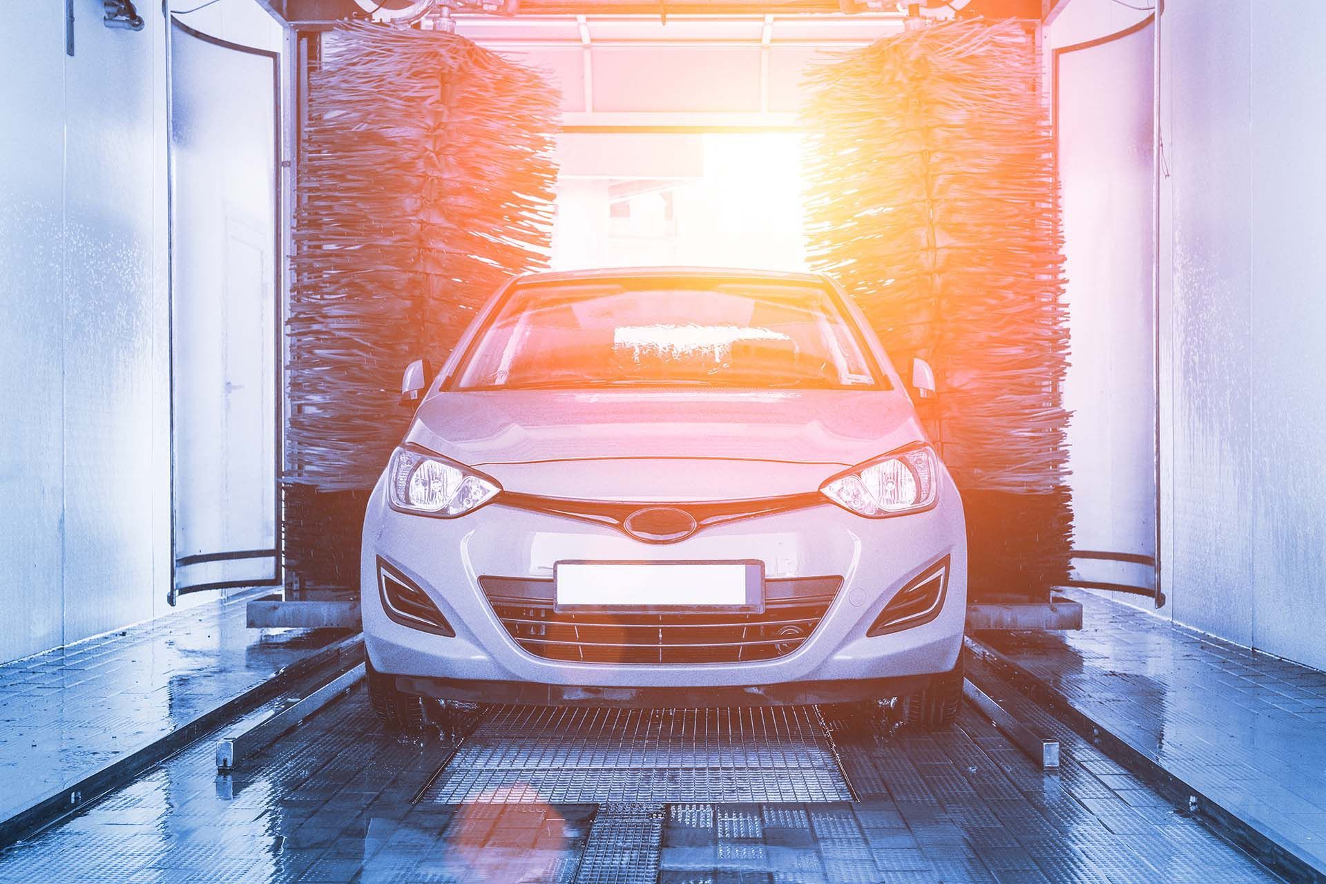 Auto brush washer clean blue car on automatic carwash station.