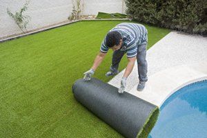 artificial grass being laid round a pool