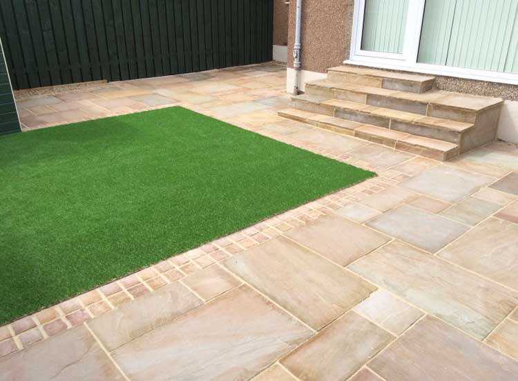 beautifully edged lawn against sandstone slab patio