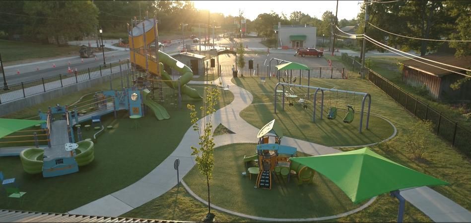Overhead view of a colorful playground with slides, swings, and shade structures in a park.