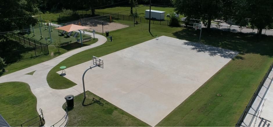 Aerial view of a park with a basketball court, walking paths, and a playground.