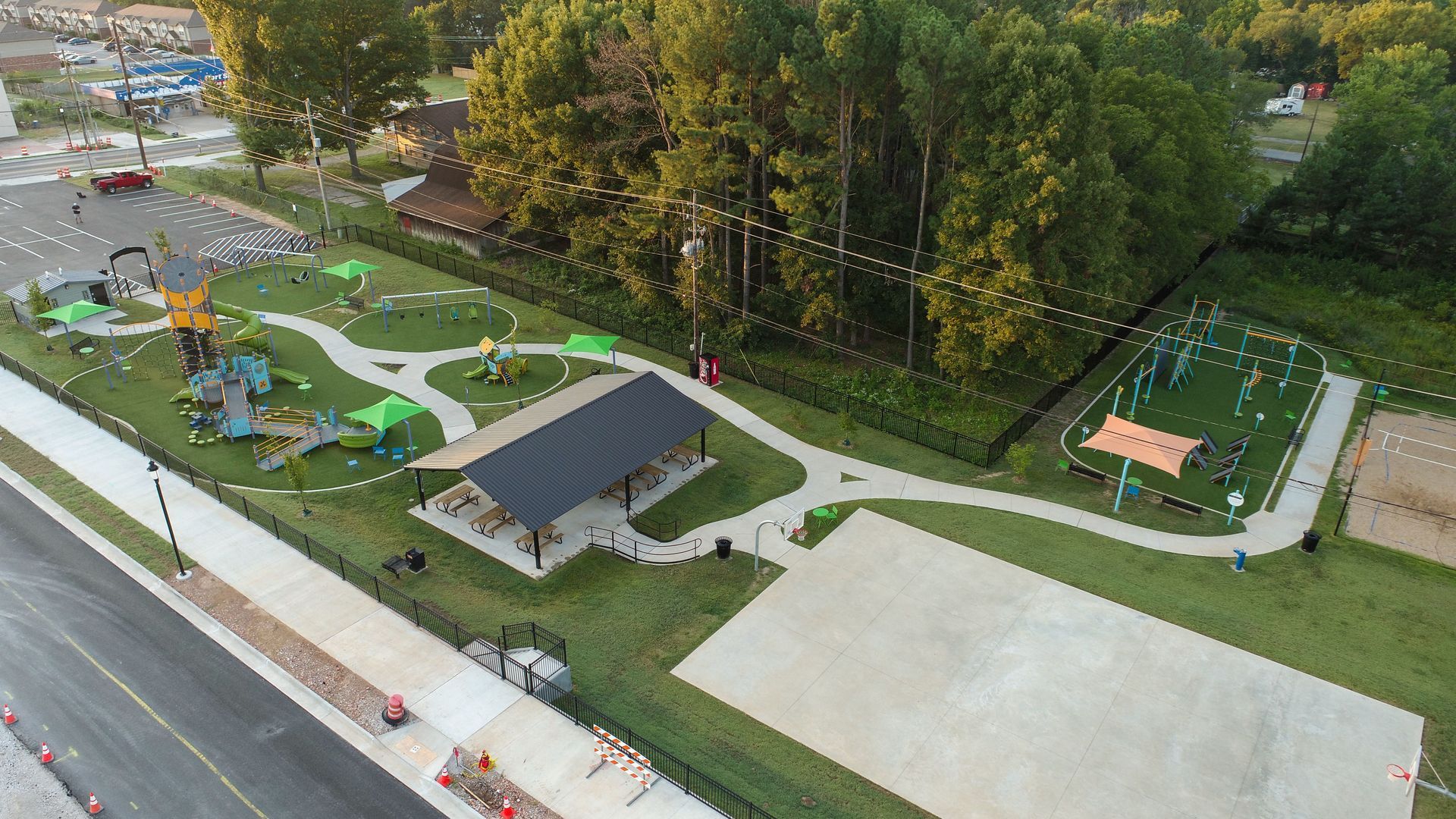 Aerial view of a park with playground, covered picnic area, pathway, and large grassy areas.