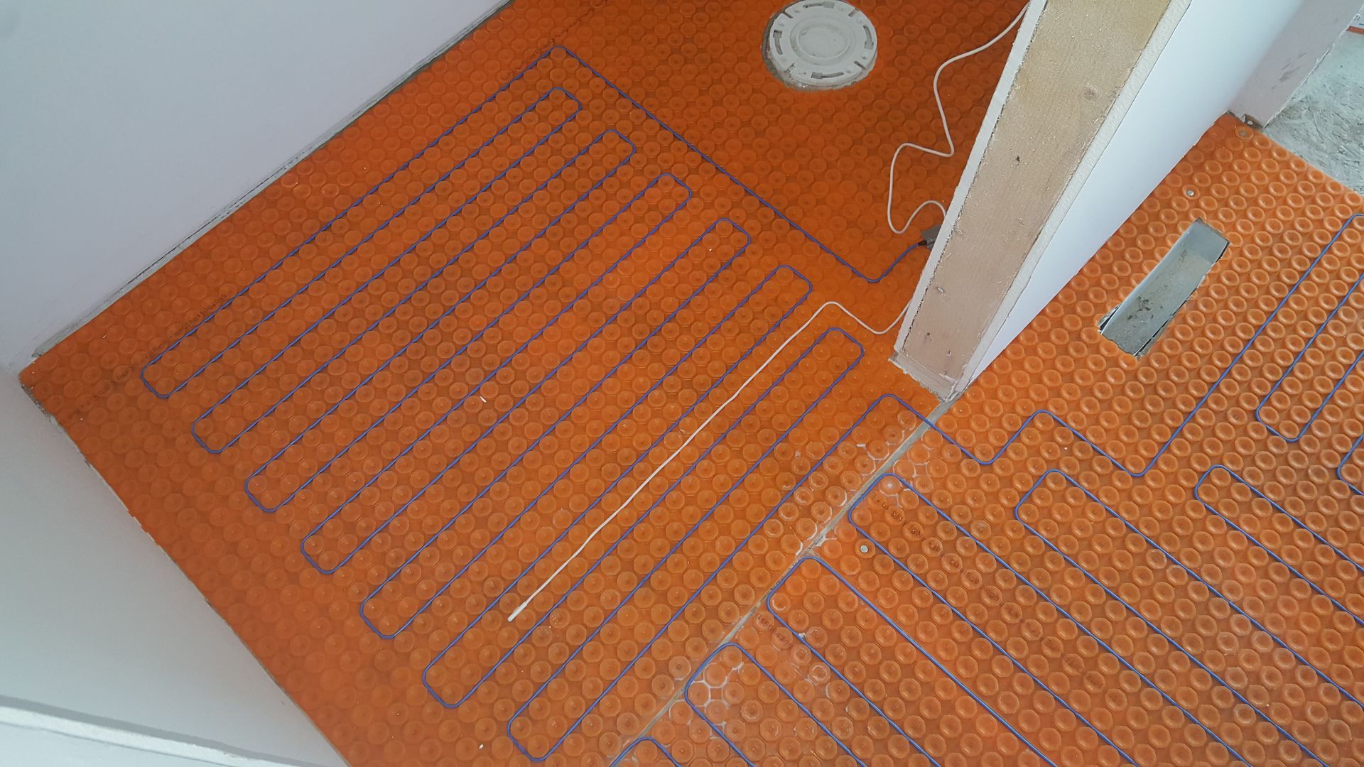 Orange heated floor matting installed in a bathroom, ready for tile.