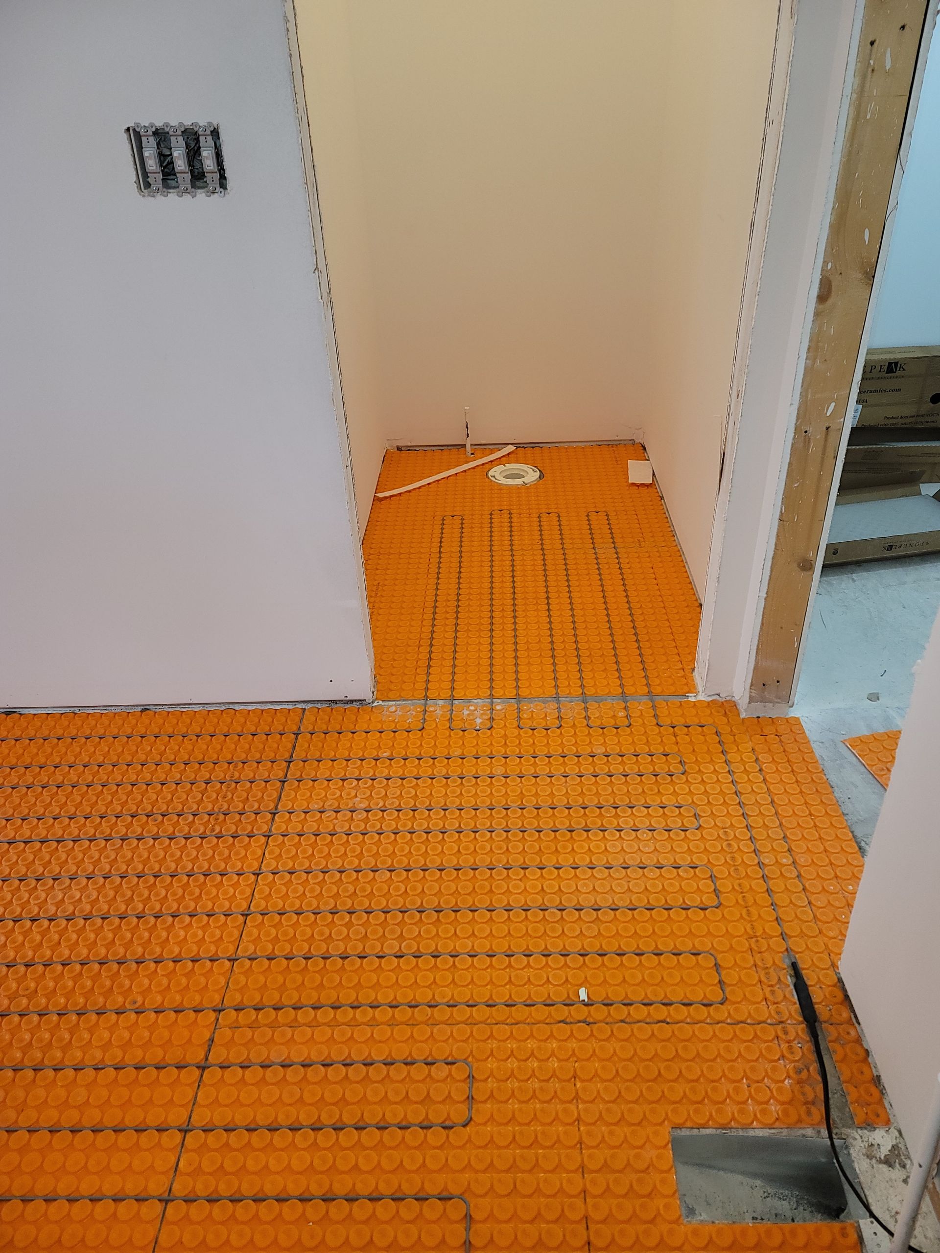 Orange radiant floor heating mat installed in a small room, ready for tile.