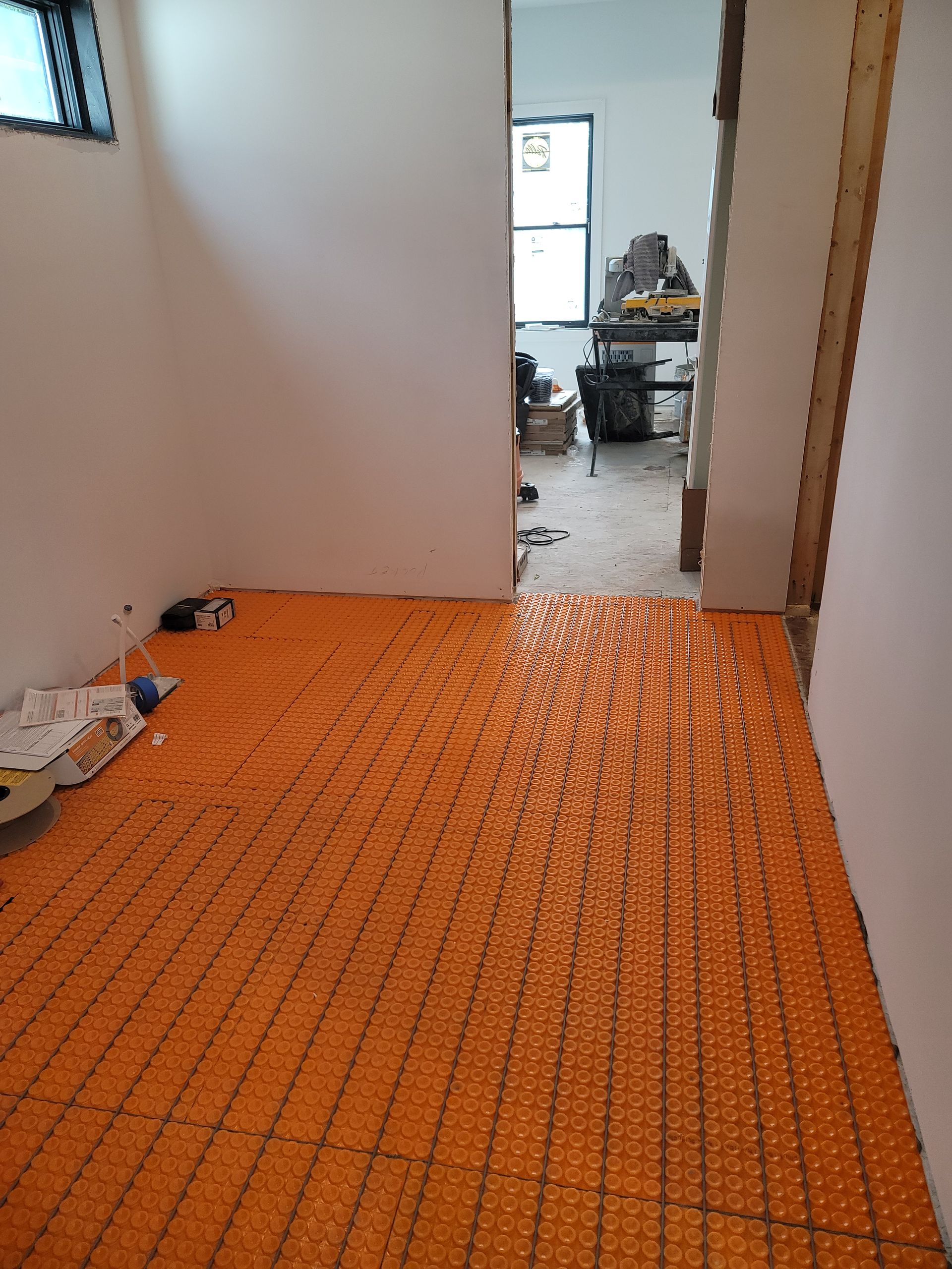Orange floor heating system installed in a room with white walls, ready for flooring.