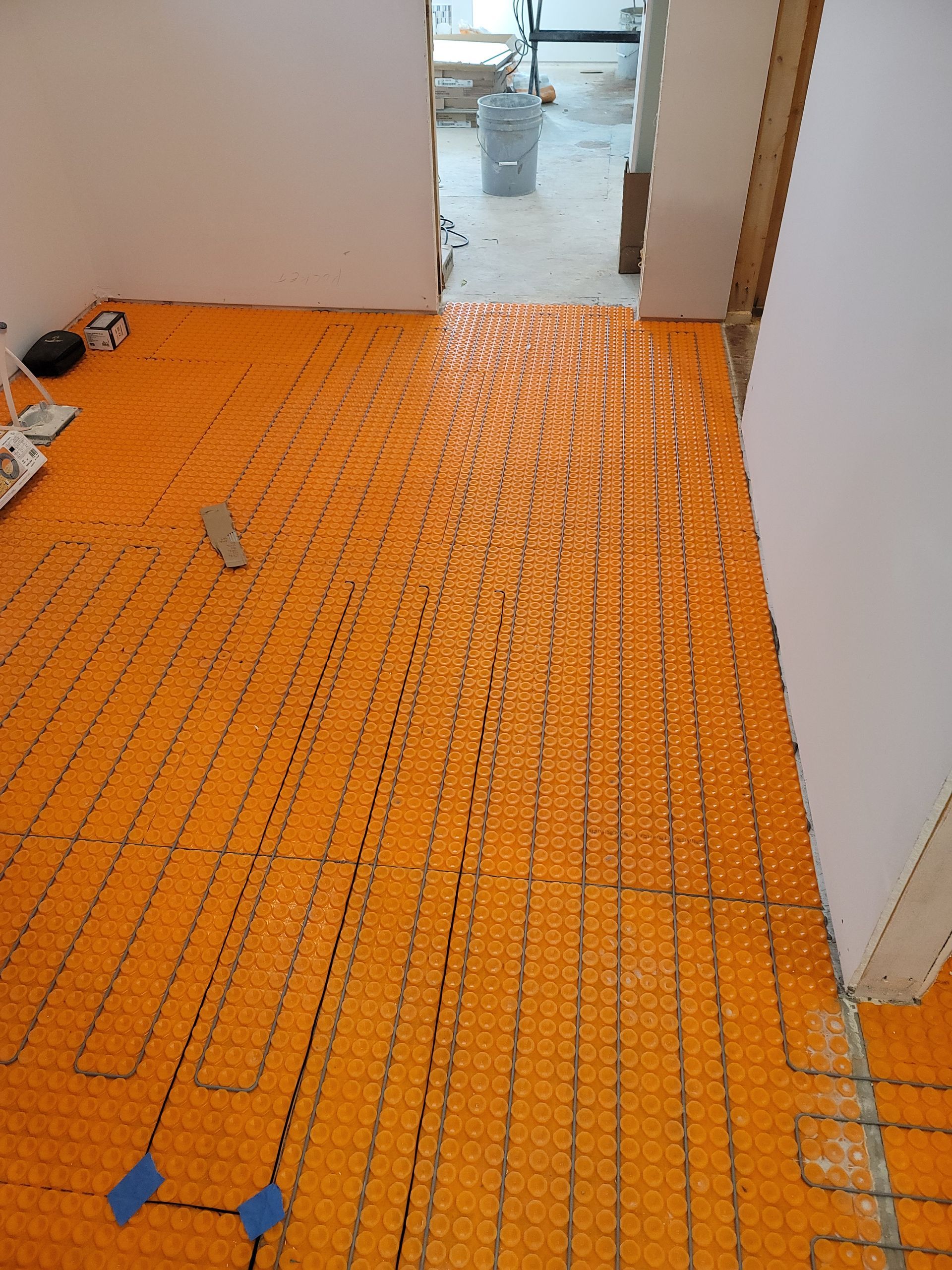 Orange radiant floor heating system installed in a room with doorways, ready for flooring.