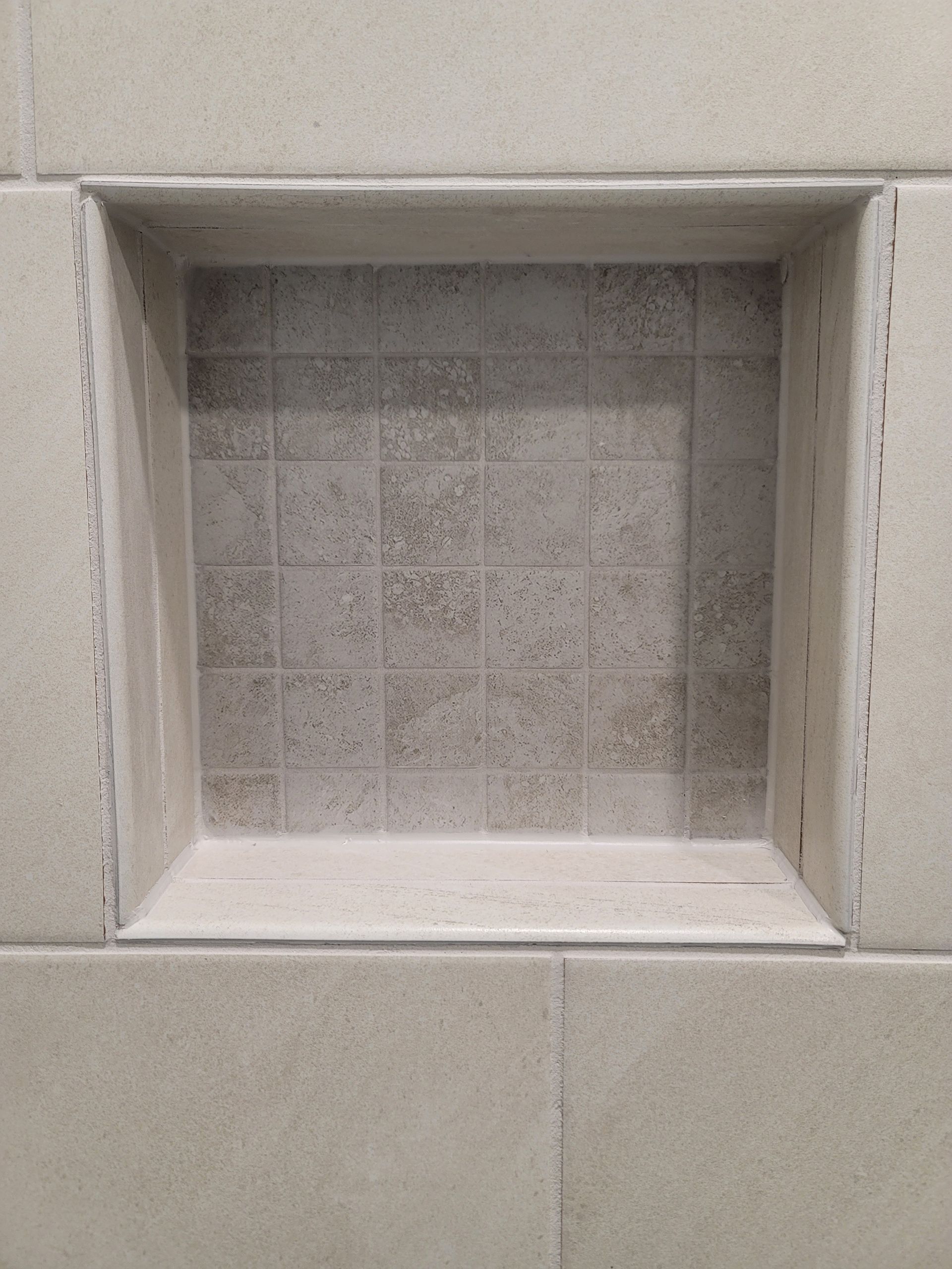 Recessed tile shower shelf. Beige tiles with gray accent tile interior.