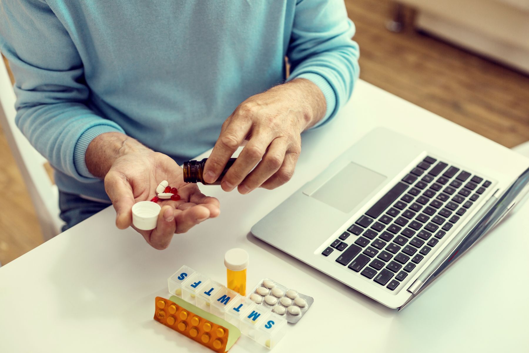 man organizing medications beside computer