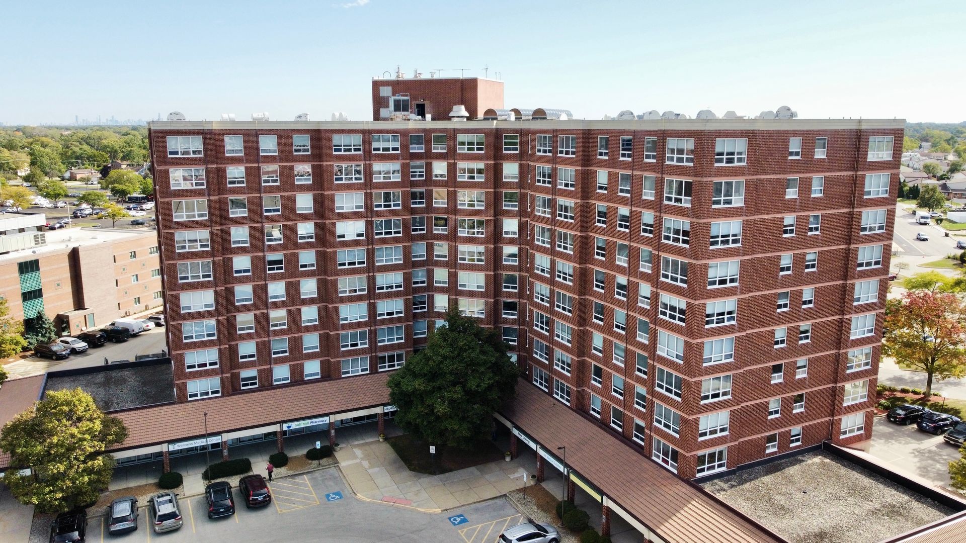 An aerial view of a large brick building with cars parked in front of it.