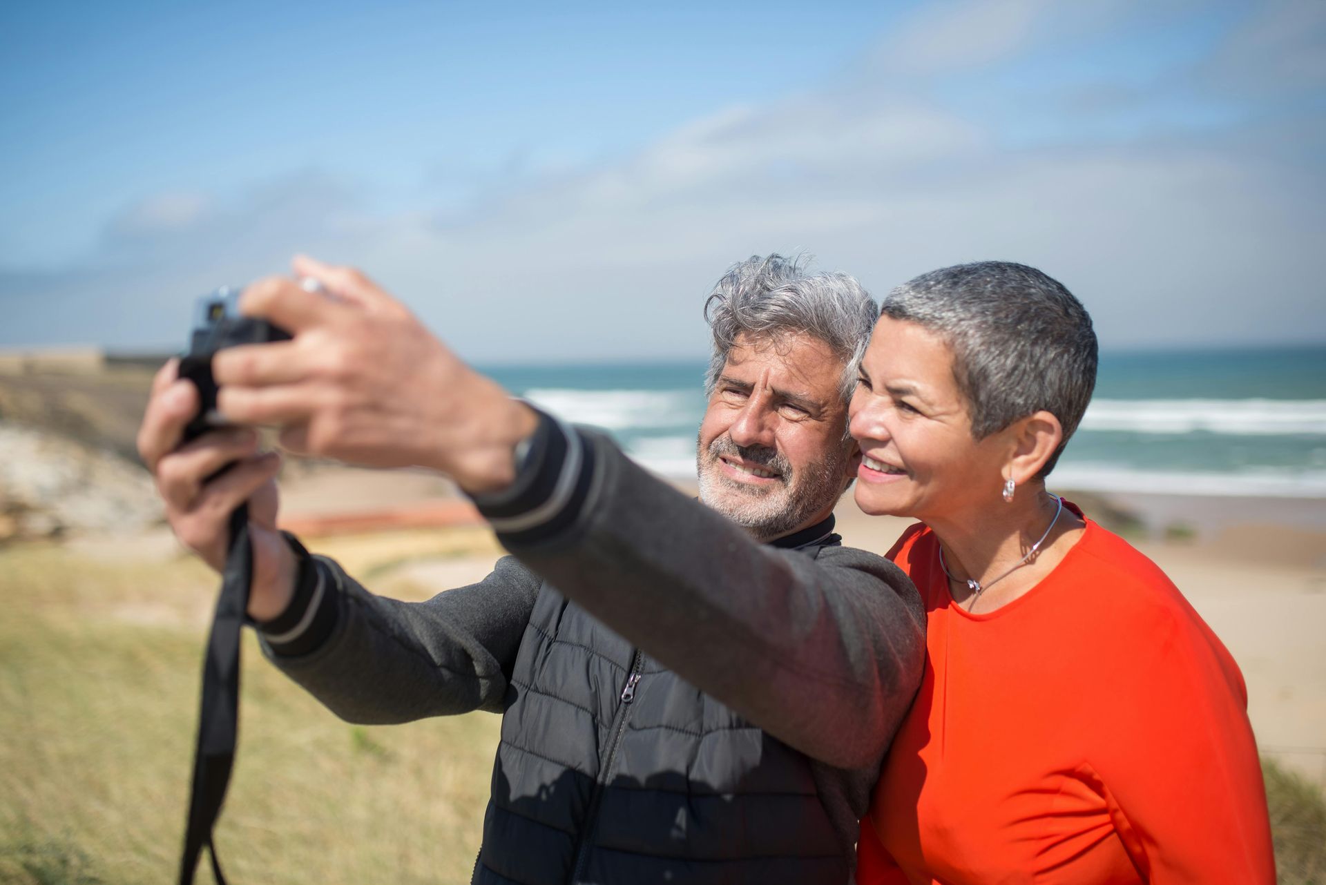 A man and a woman are taking a selfie on the beach.