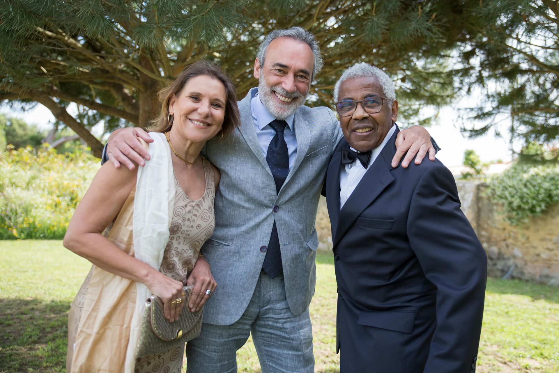 A man and two women are posing for a picture in front of a tree.
