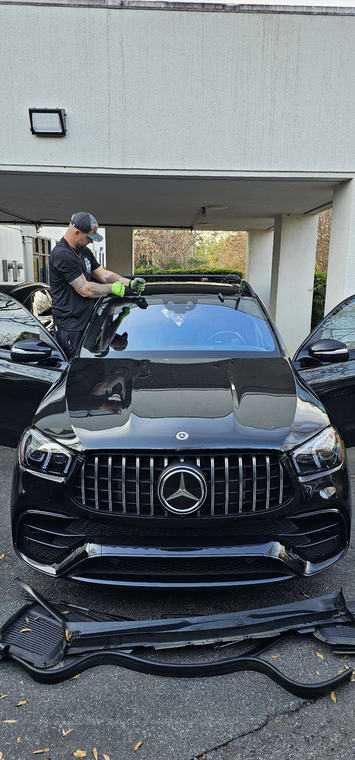 Person in blue gloves using a suction cup to install a car windshield.