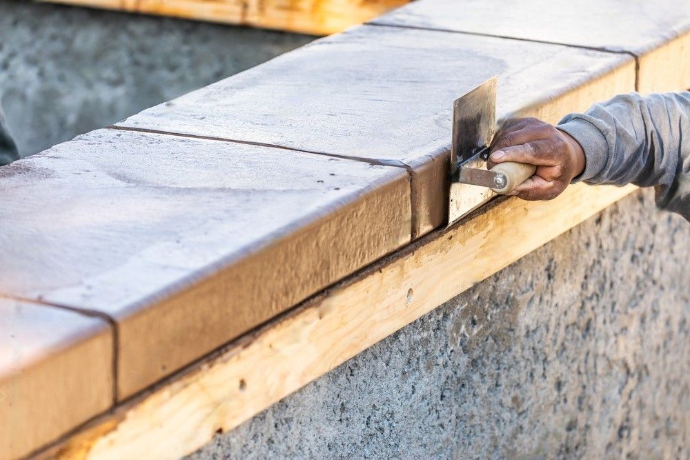 A person is using a trowel on a concrete wall.