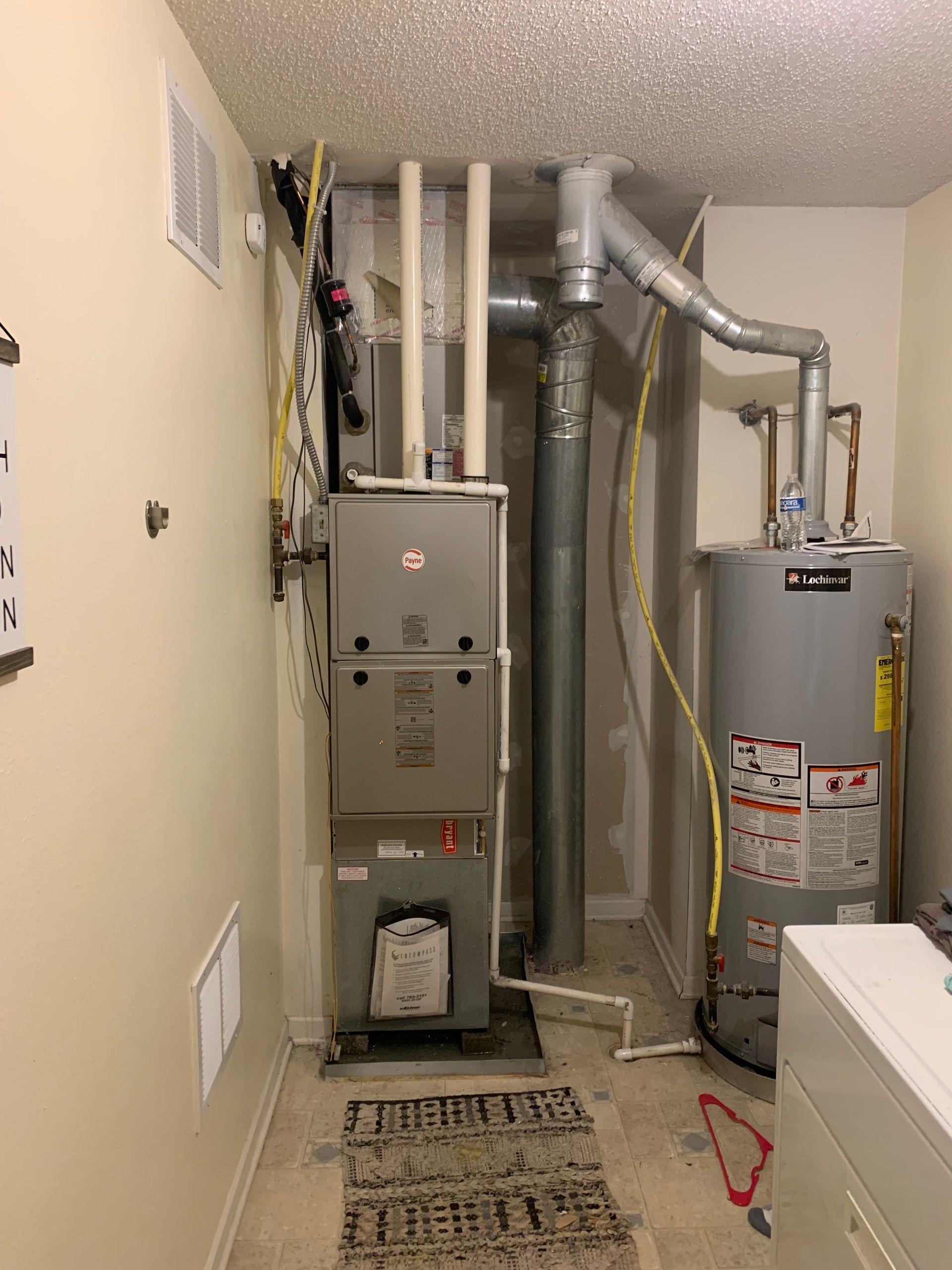 Furnace and water heater in a utility room with ductwork and a white ceiling.