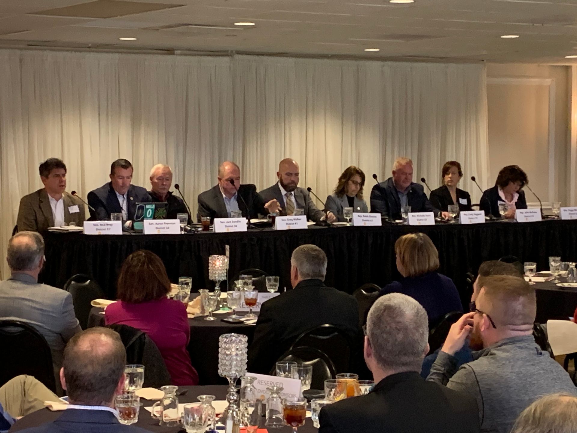 Panel of people seated at a table, addressing an audience at an event.