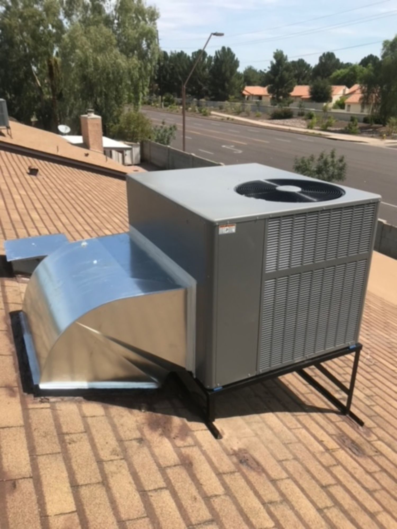 A large air conditioner is sitting on top of a brick roof.