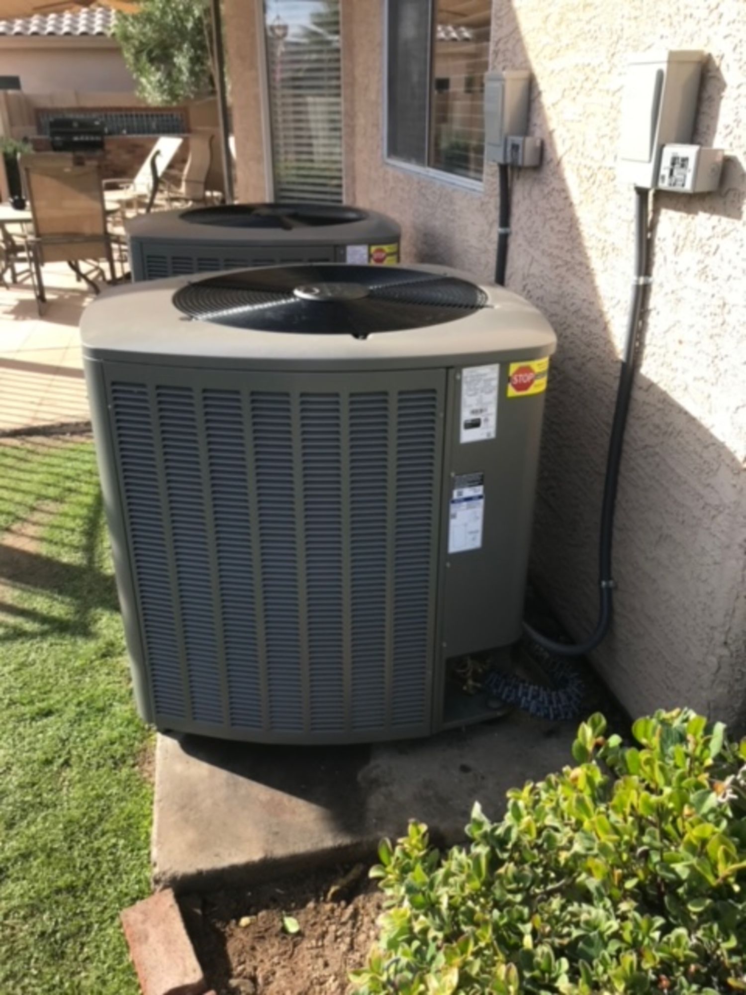 Two air conditioners are sitting outside of a house