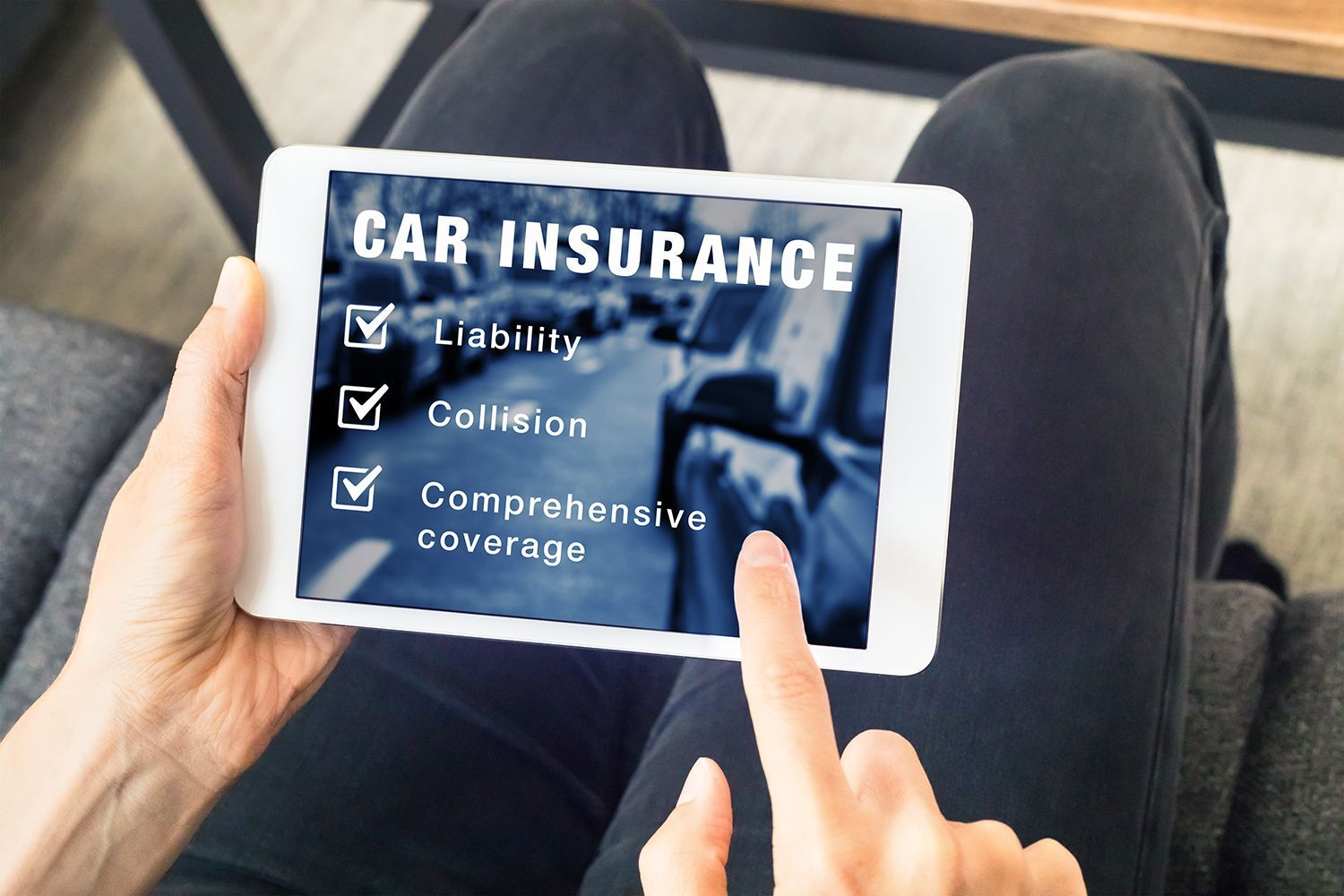 Hands using a tablet showing car insurance coverage options with checkboxes.