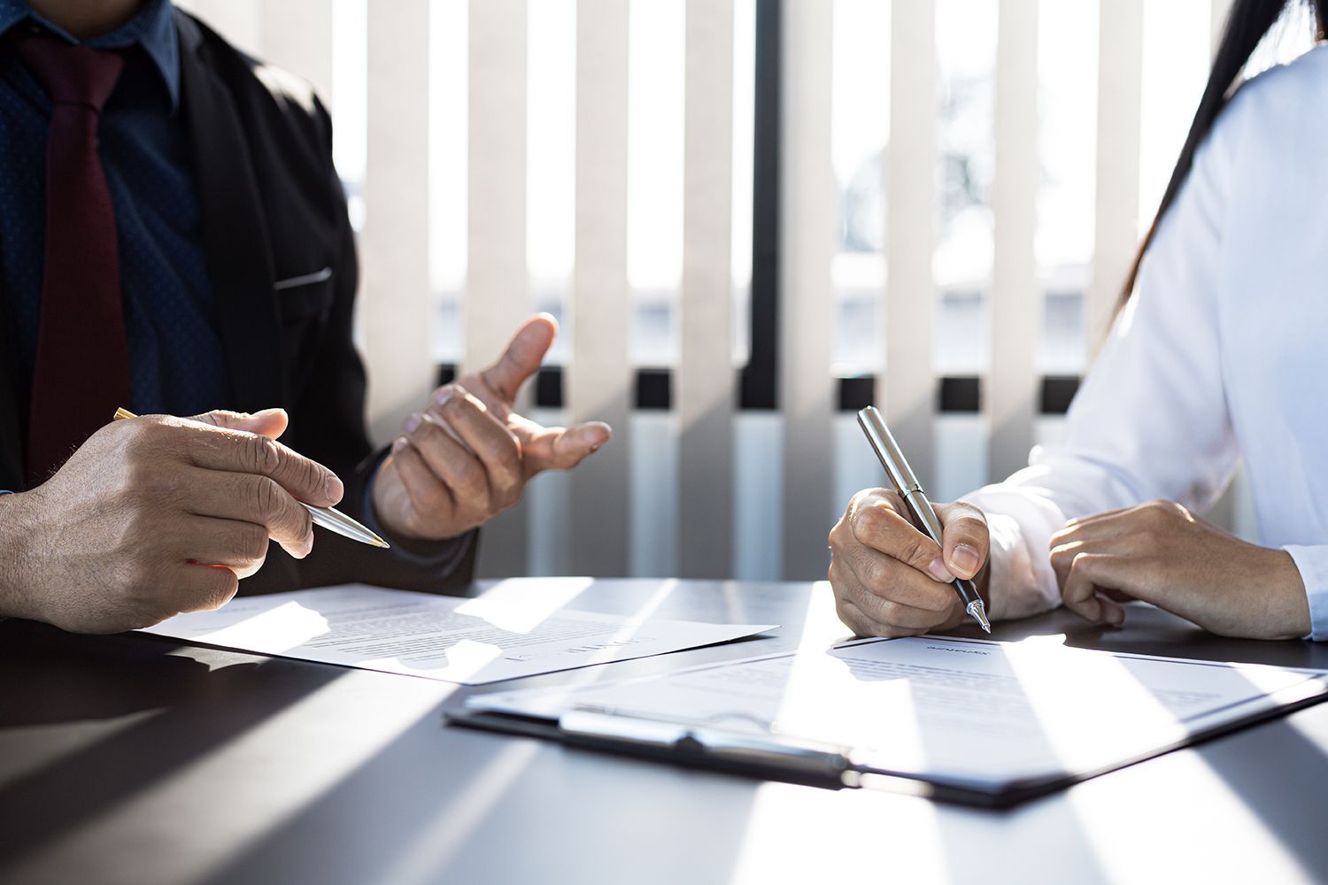Two people in business attire discussing documents at a conference table Two people in business attire discussing documents at a conference table