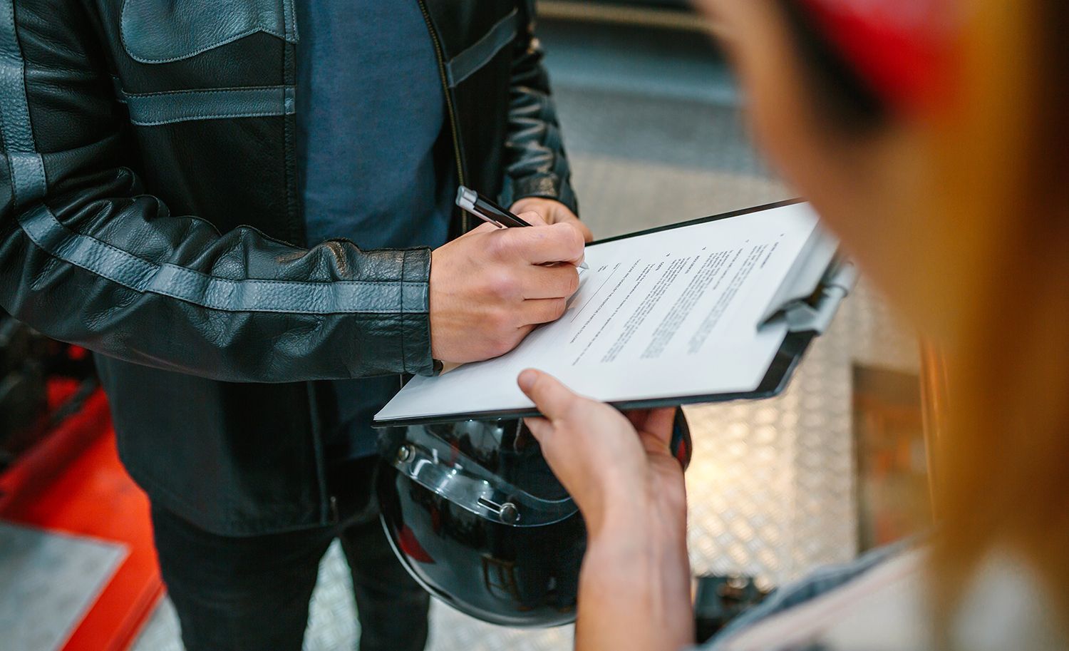 Person filling out a clipboard form while standing outdoors in a black jacket Person filling out a clipboard form while standing outdoors in a black jacket